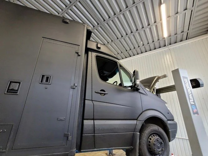A black utility van in a garage with the hood open
