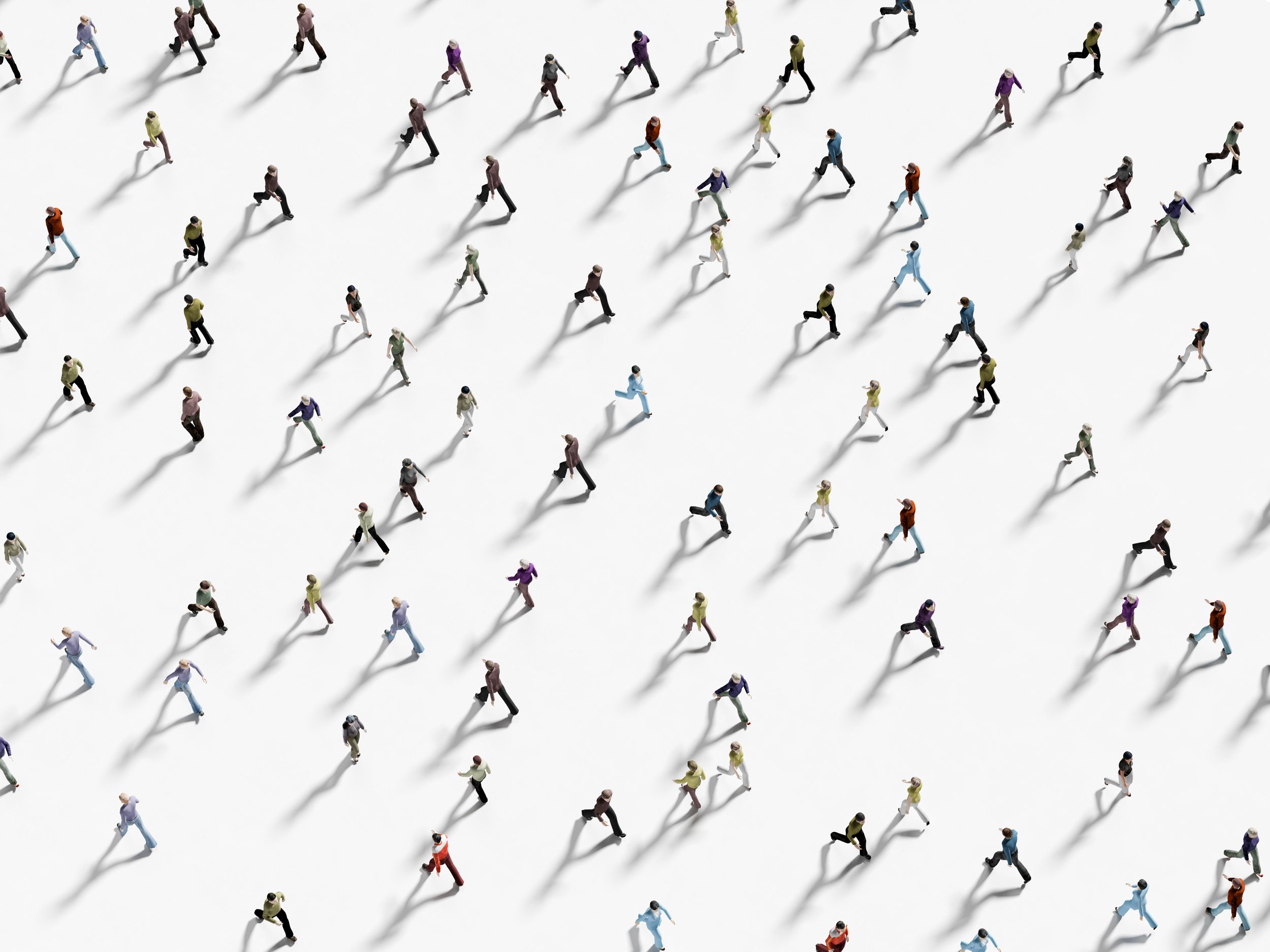 A diverse group of miniature people walking in different directions on a white surface, casting long shadows.