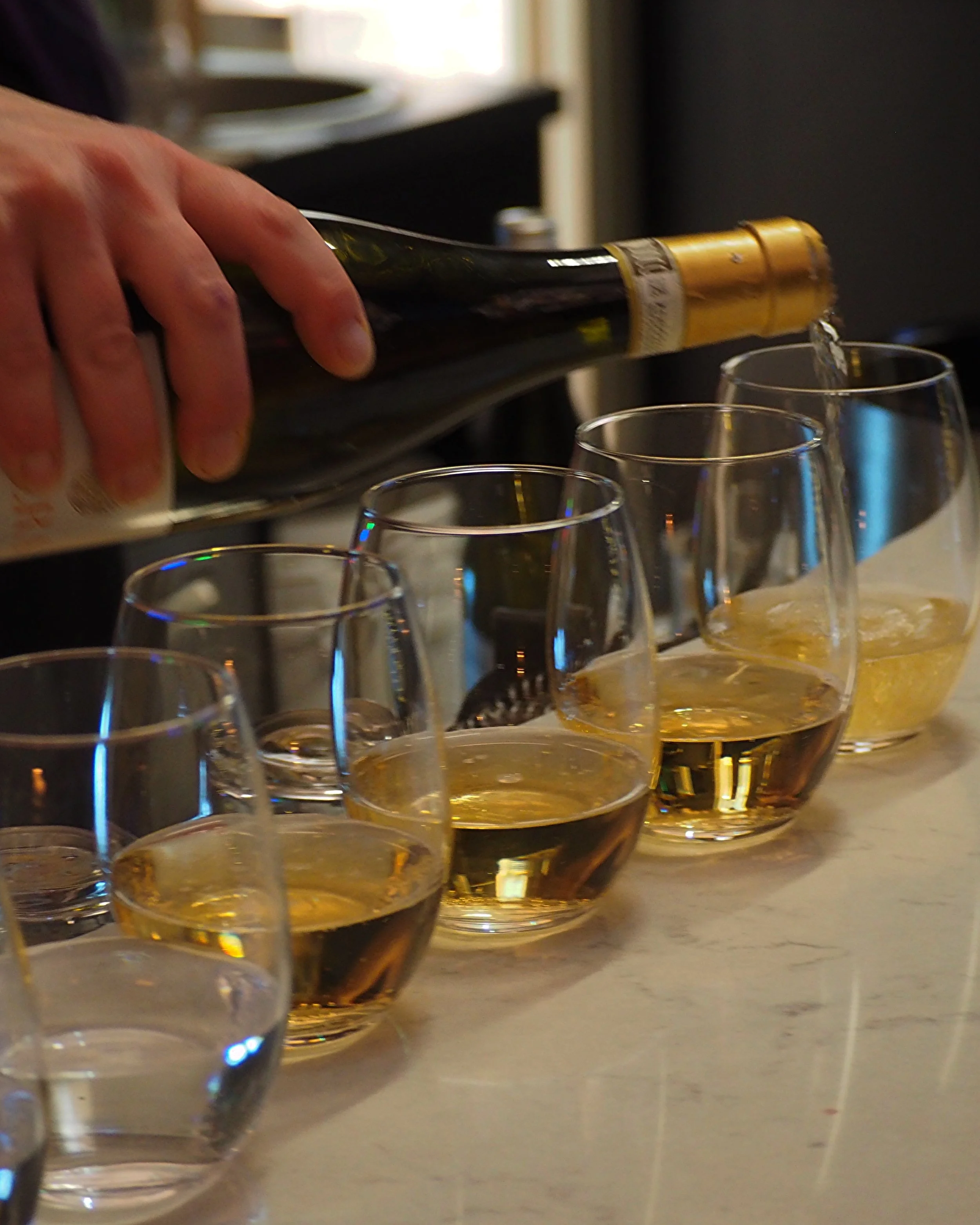 Person pouring wine into glasses on a table.
