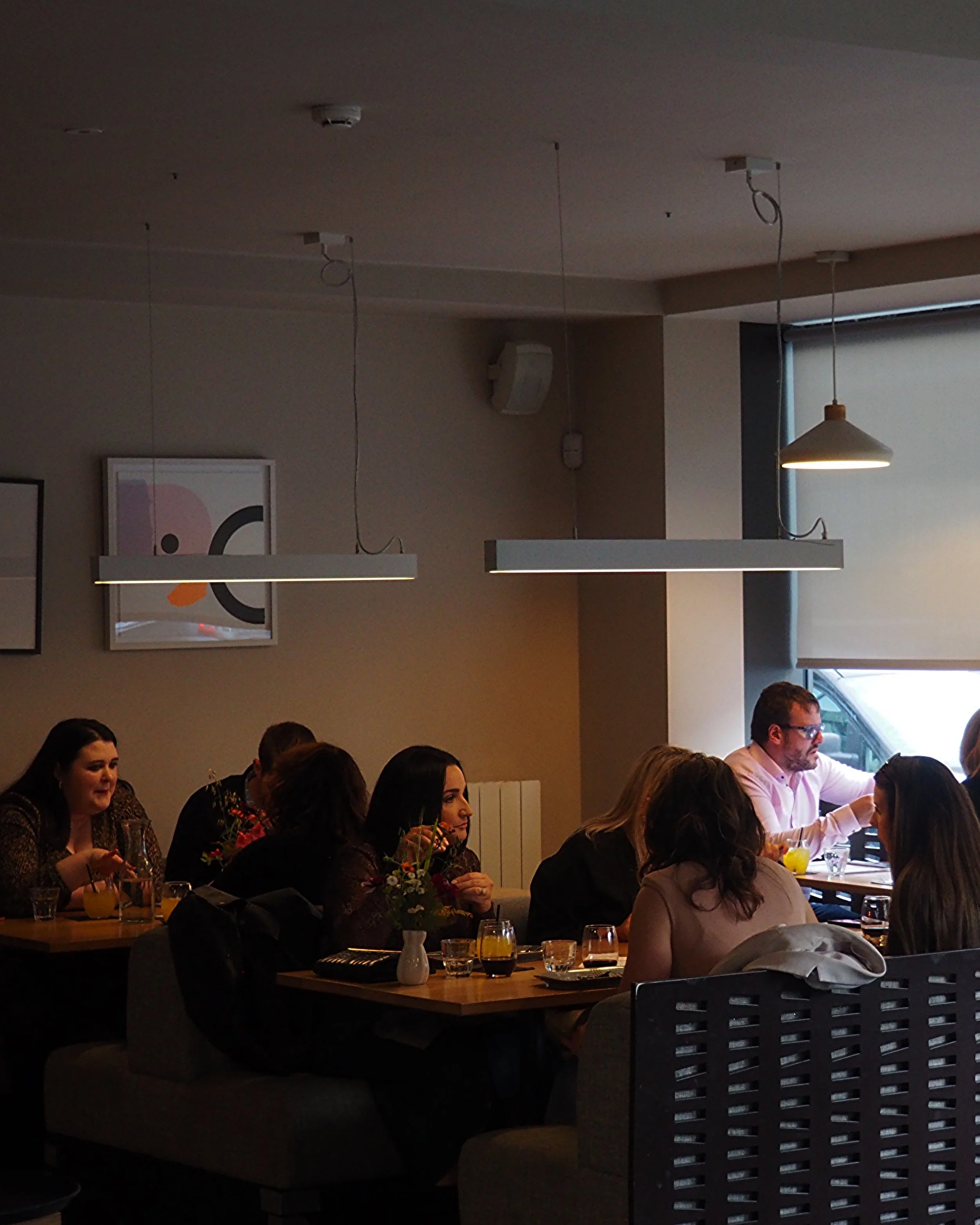 People dining in a cozy restaurant with low lighting and modern decor.