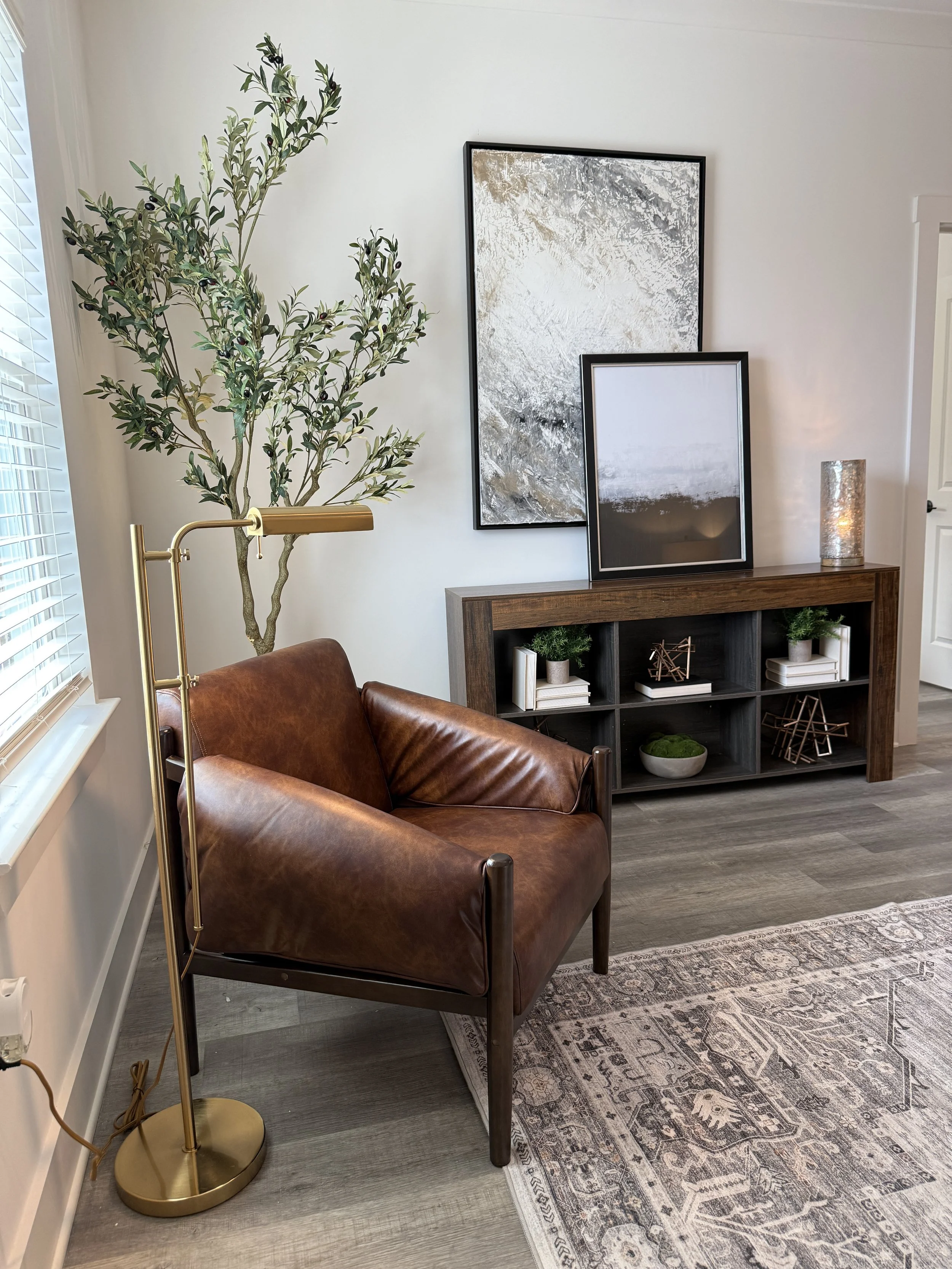 Modern dining room with white table, animal print and neutral fabric chairs, black sideboard, wood accents, and a large vase with green foliage.