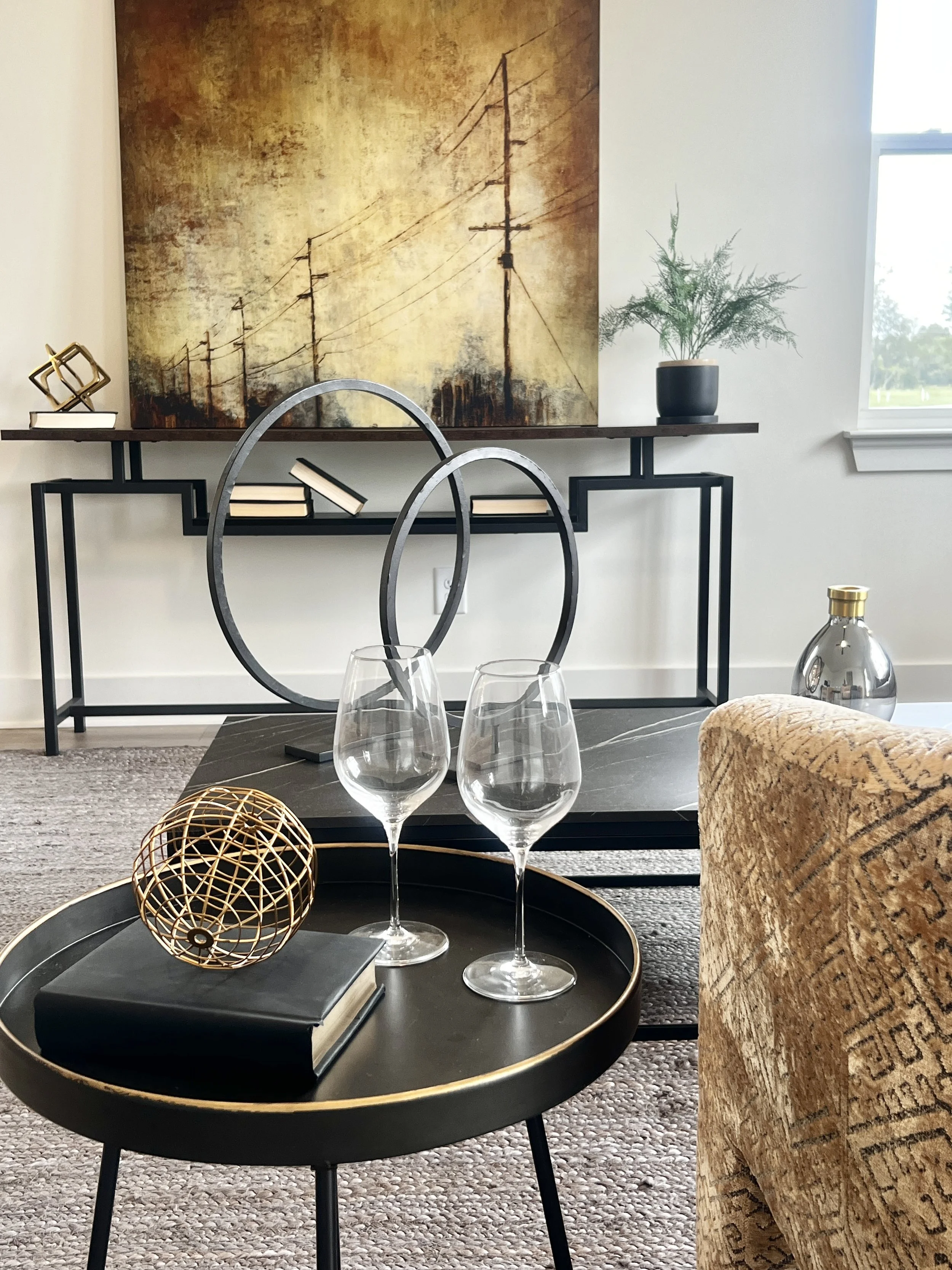 Living room with a brick fireplace, white walls, modern furniture, a wooden coffee table, a fireplace with a fire burning, abstract artwork on the wall, and indoor plants.