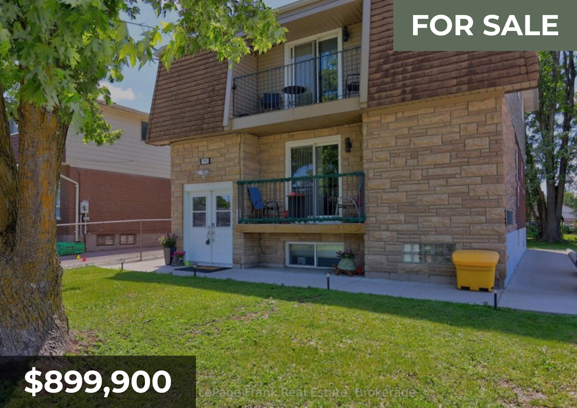 A multi-story residential building with brick and siding exterior, with small balconies, surrounded by green grass and trees, with a yellow trash bin nearby, for sale at $899,900.
