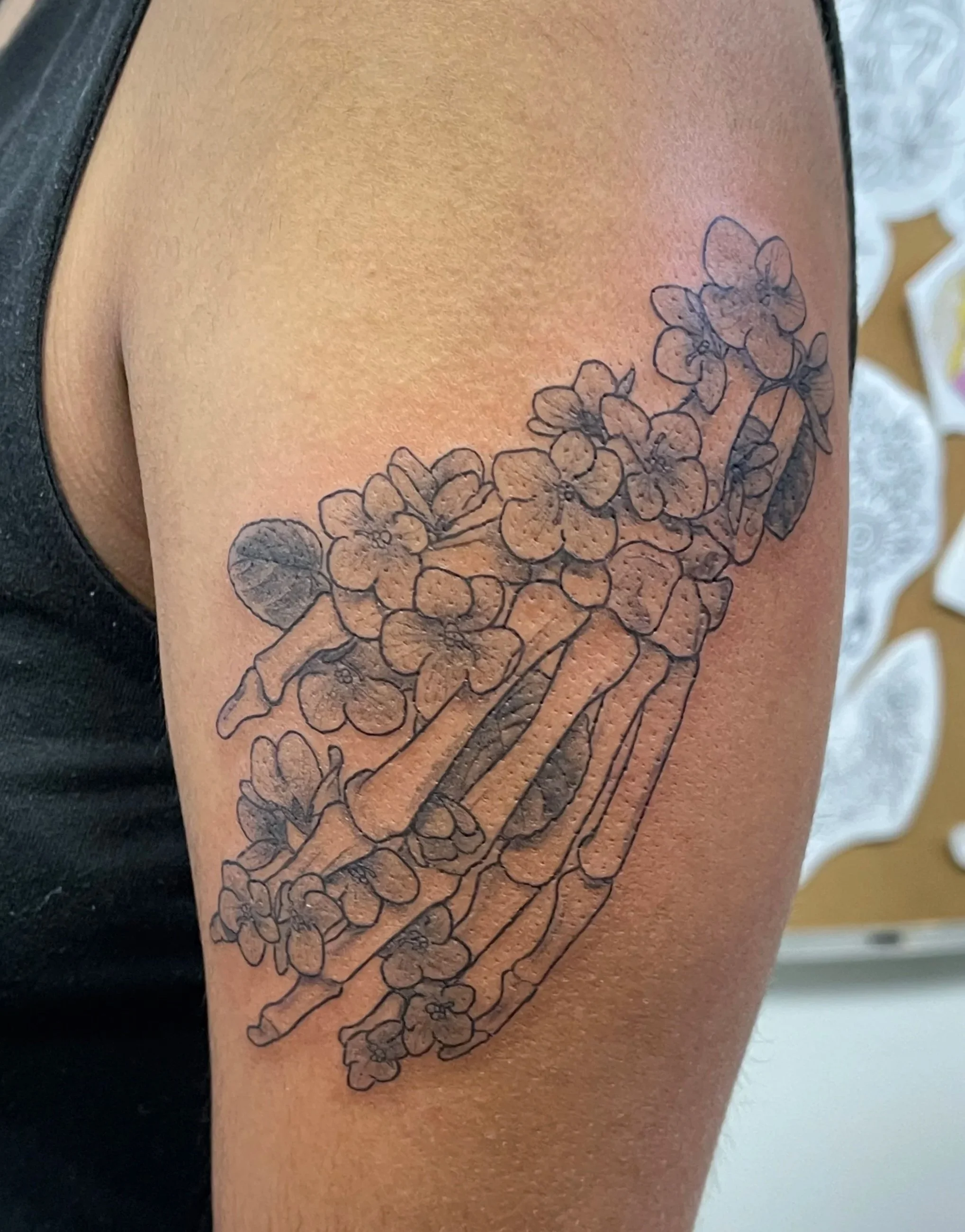 Skeleton hand with flowers on a person’s upper arm