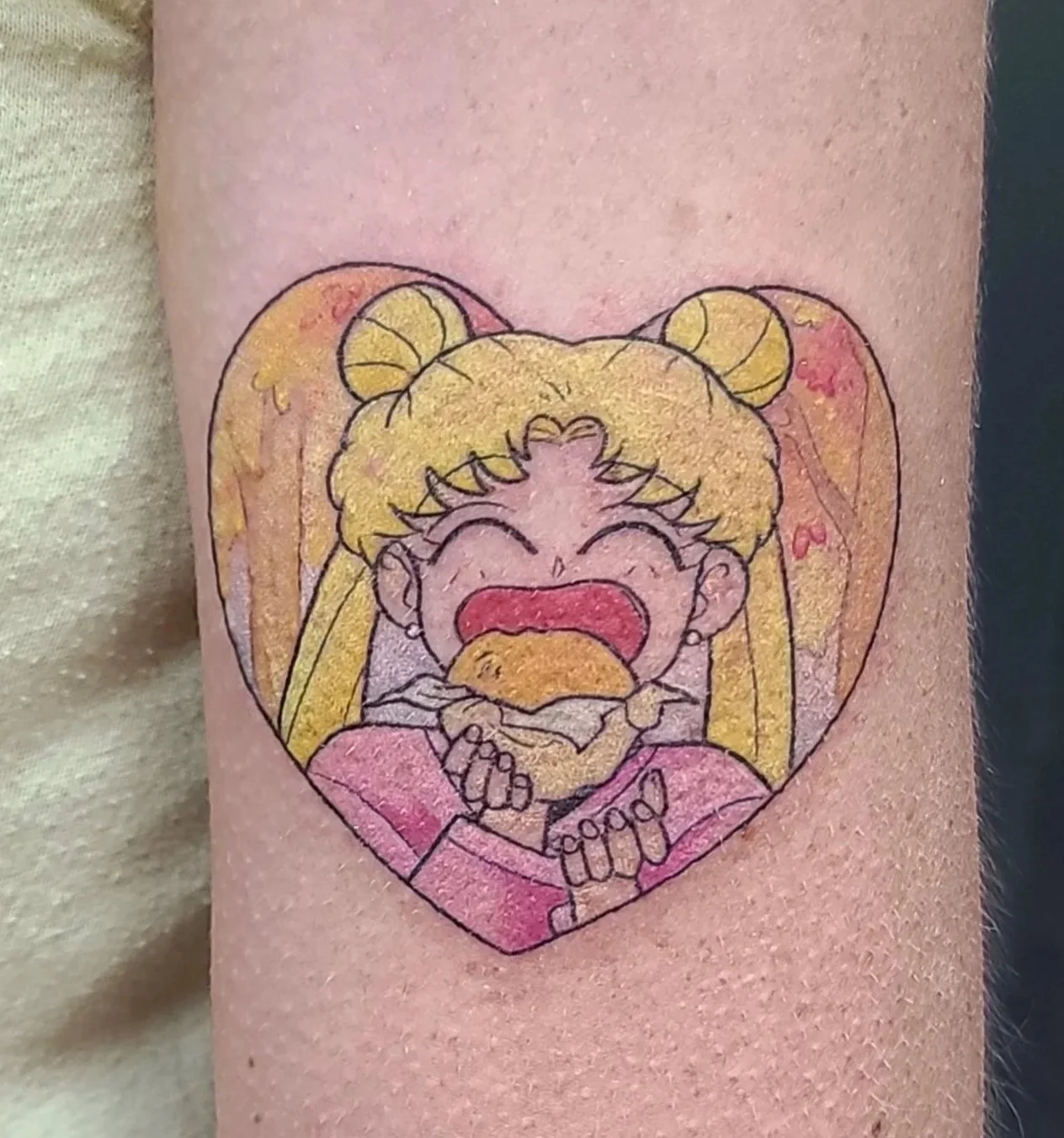 Tattoo of a cartoon girl with blonde hair in pigtails inside a pink heart shape, crying and holding a Burger King burger.