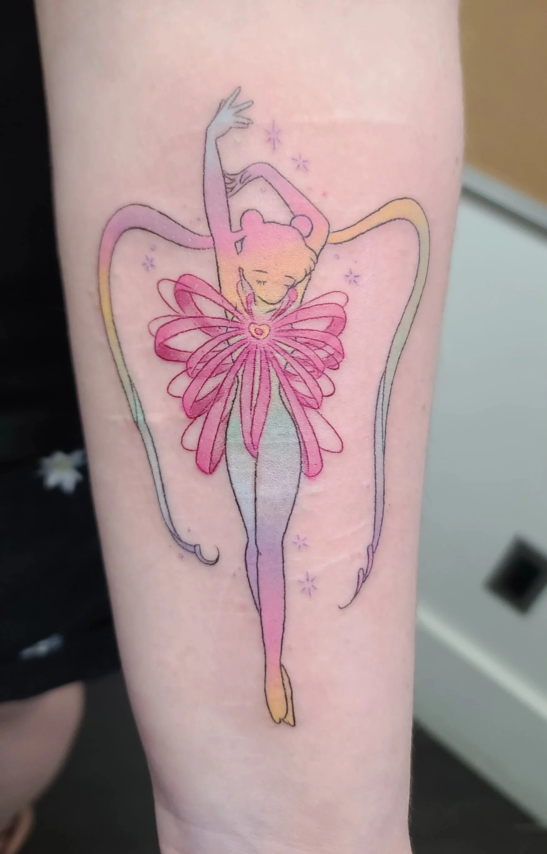 Tattoo of a ballet dancer with fairy wings, wearing a pink tutu, with her arms raised gracefully, surrounded by small stars, with a heart in the center of her chest.