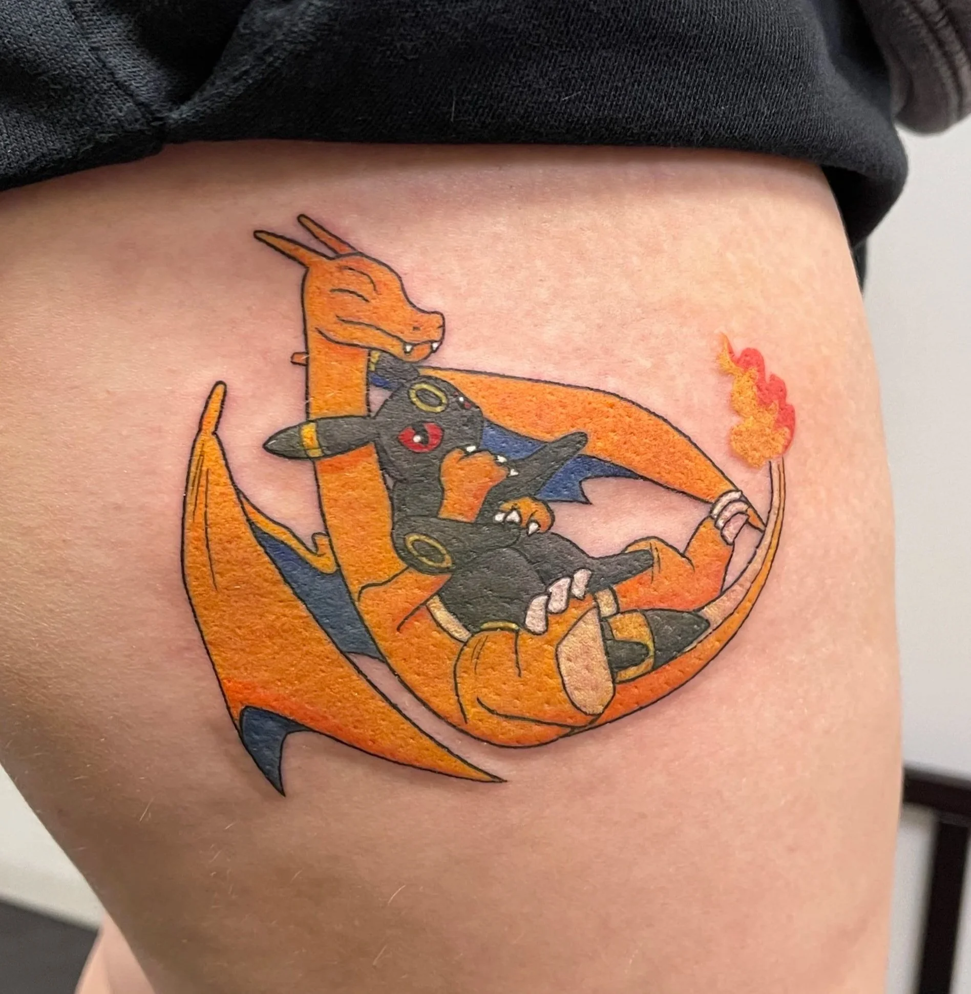 Tattoo of Charizard and Lucario from Pokémon on person's upper thigh.