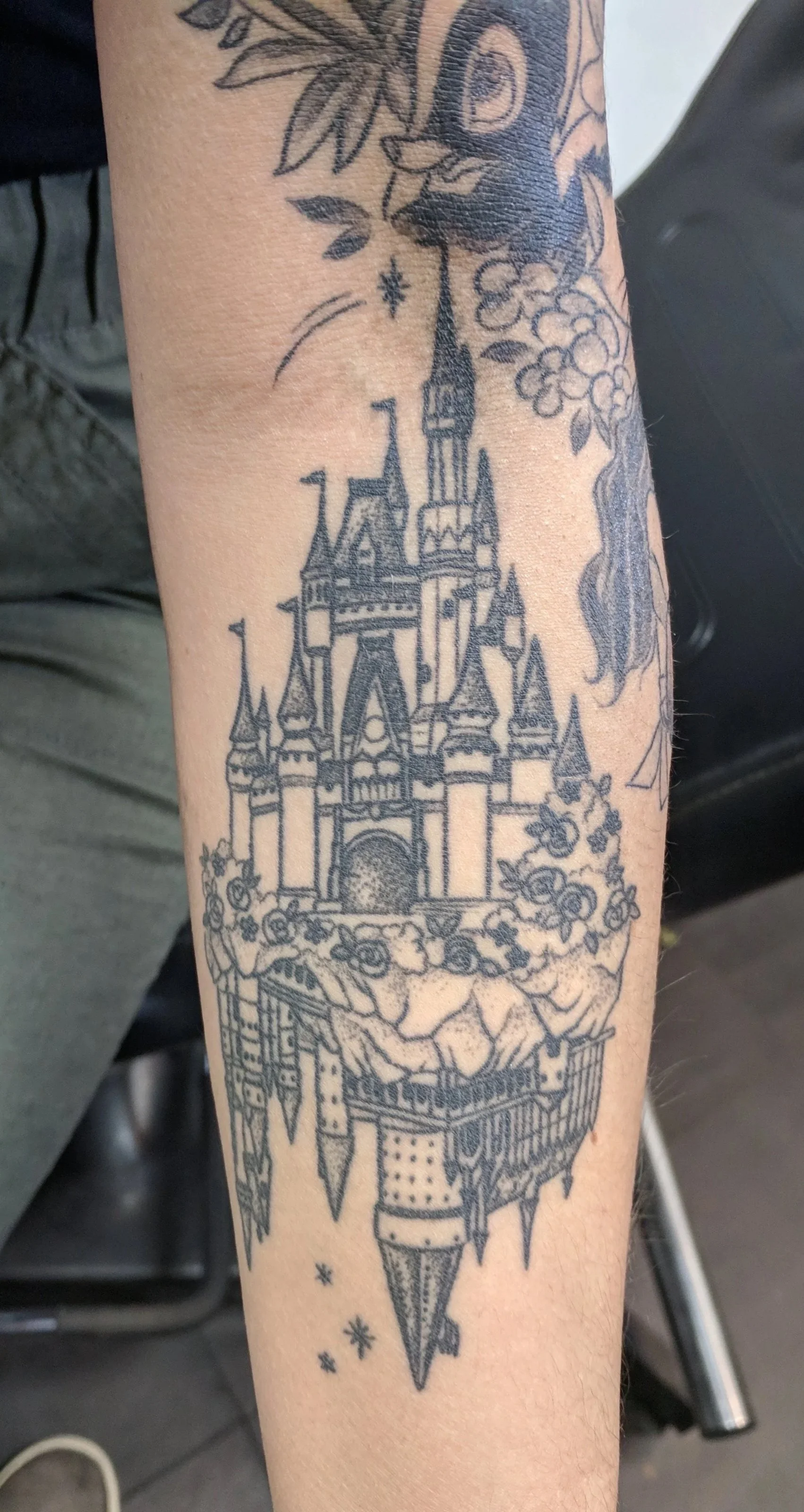 Tattoo of a castle with flying flags, clouds, stars, and floating rocks.