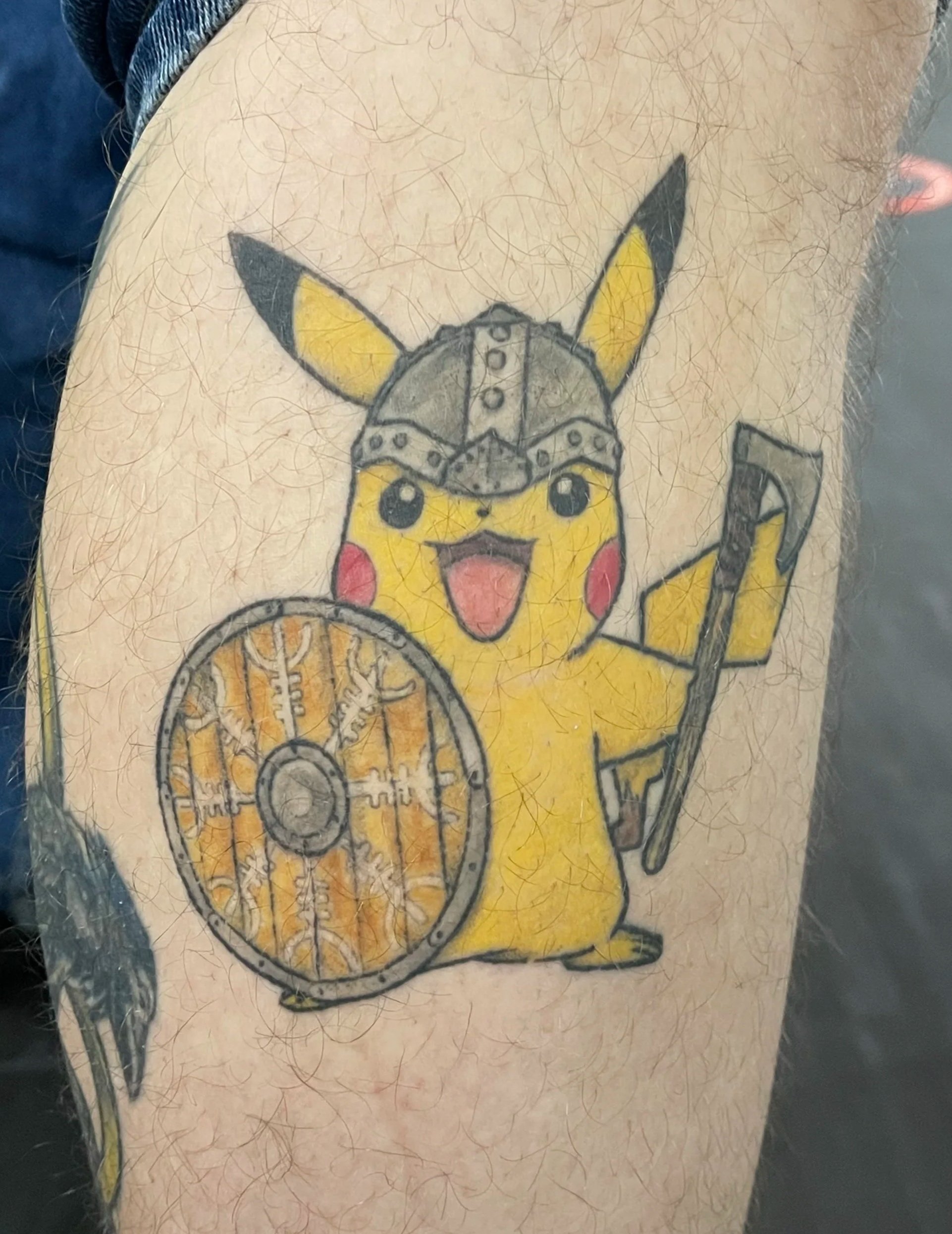 Tattoo of Pikachu dressed as a Viking with a helmet, shield, and spear.