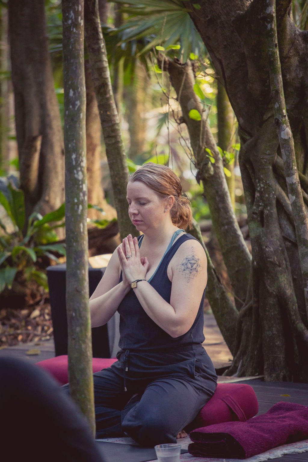 Photo of Sarah Kelly meditating in the jungle at Palmaia