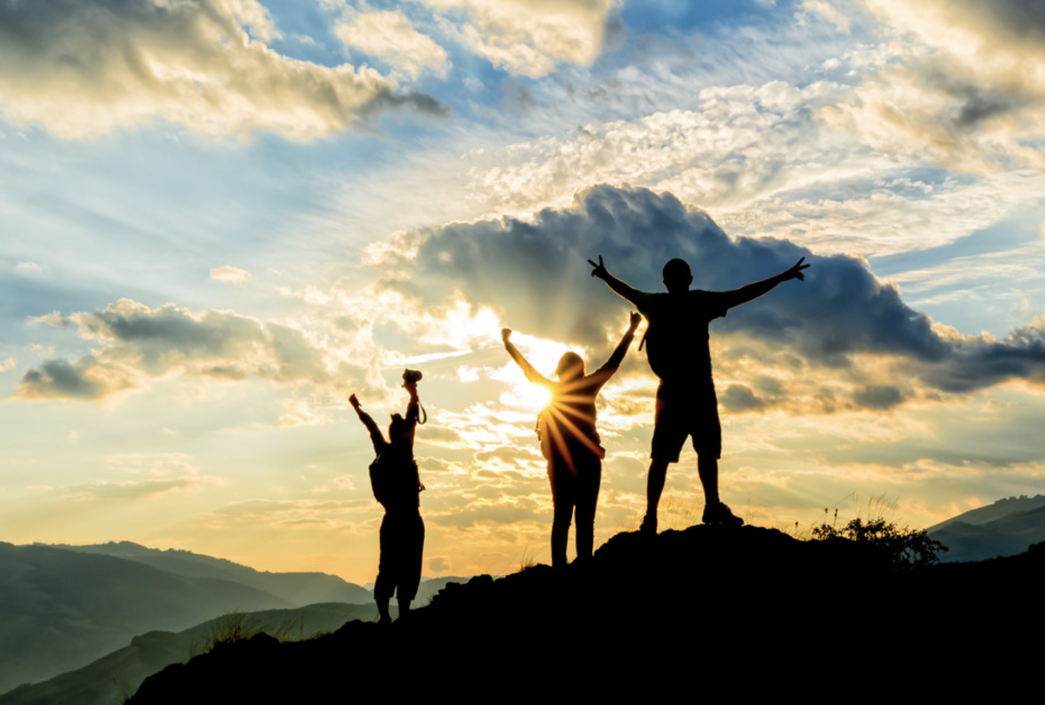 Hikers on top of hill  with hands up during sunset