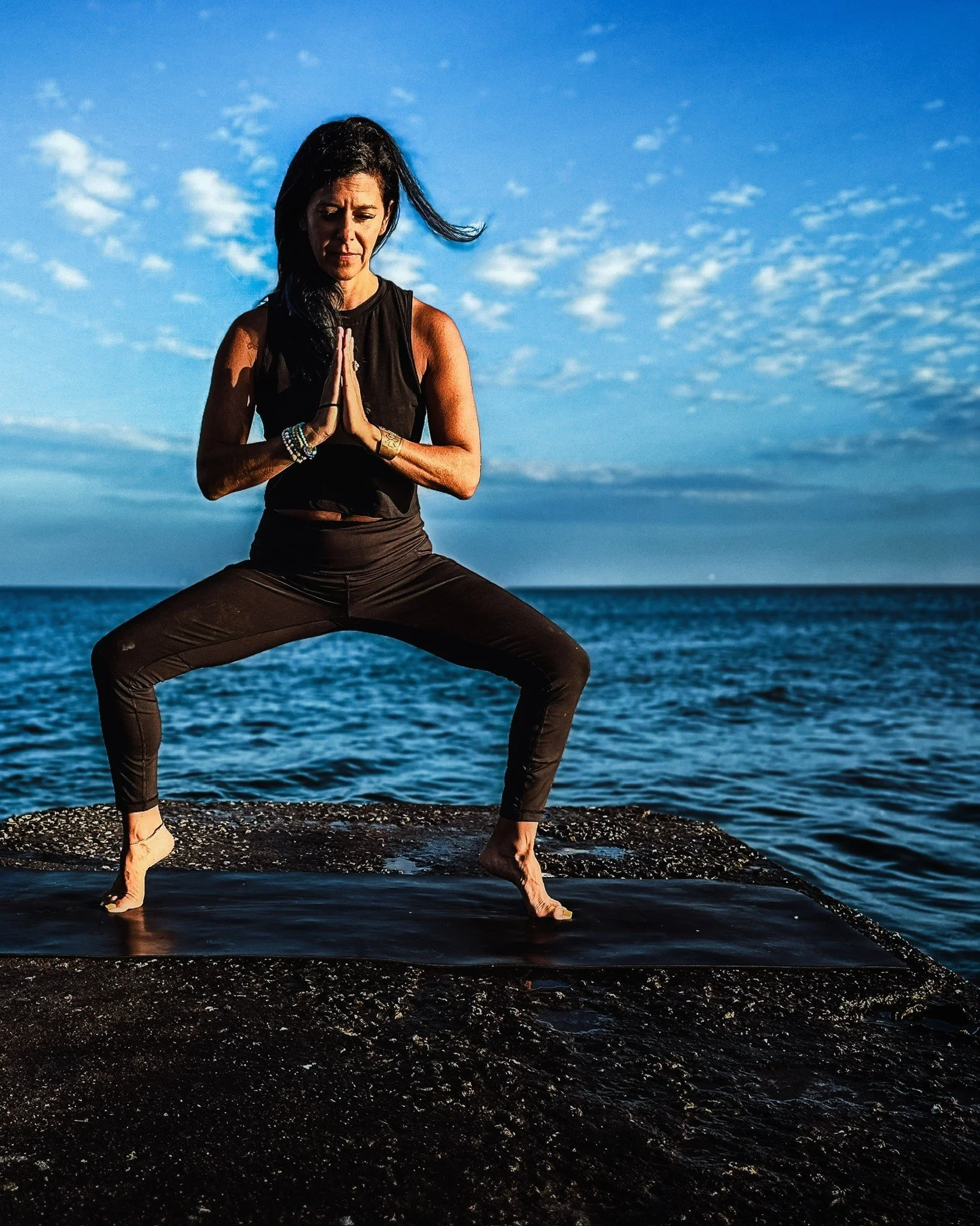 Kristina doing a yoga pose with a water view in the background.
