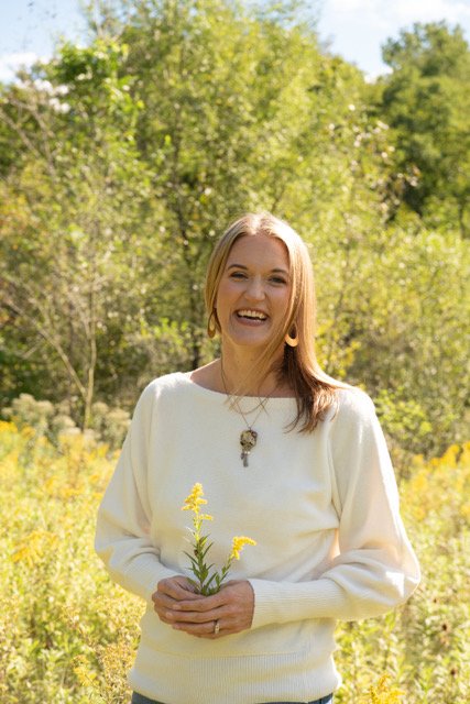 women smiling holding a flower in a field