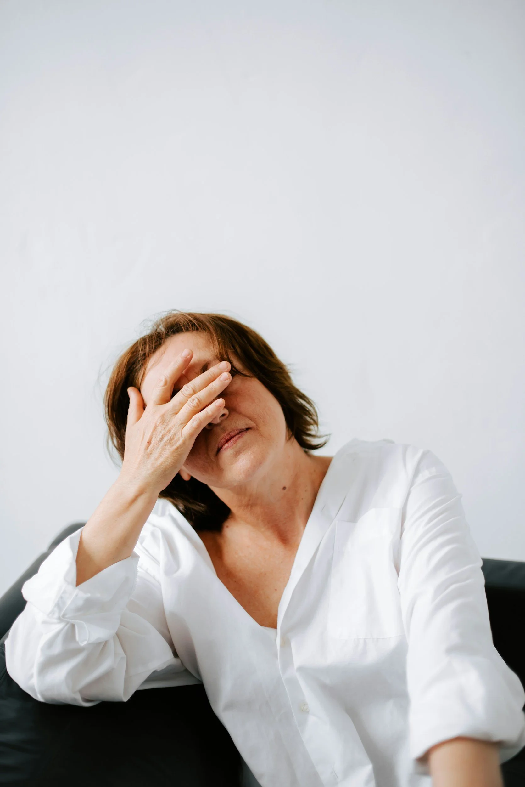 Woman sitting quietly with eyes closed, hand on chest, representing nervous system dysregulation and somatic awareness.