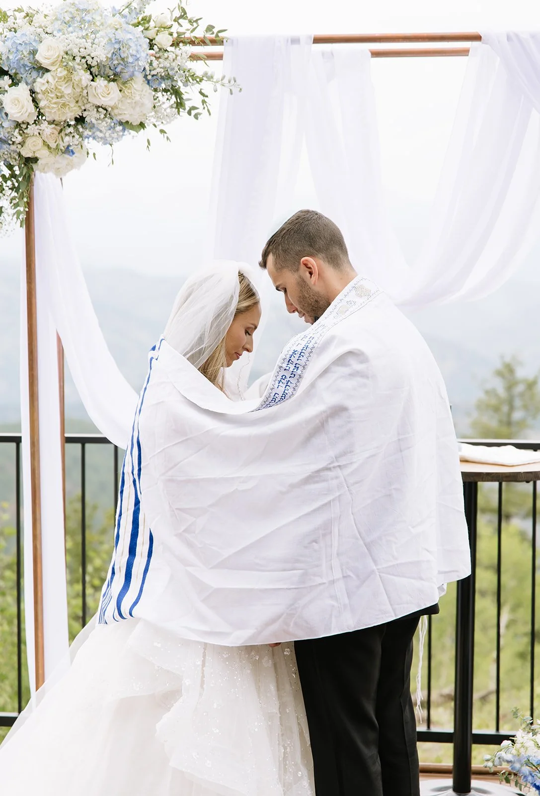 A jewish wedding ceremony beneath a prayer shawl