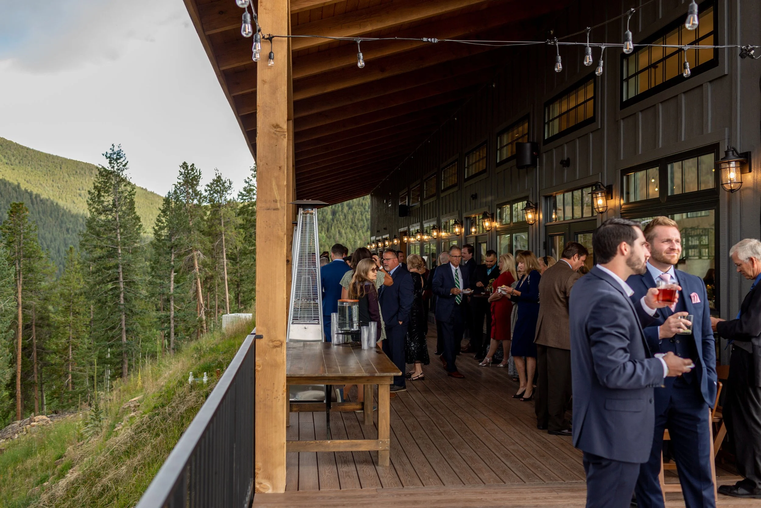 Guests enjoy cocktail hour at north star gatherings - the deck is wooden with heaters and overlooks a mountain ridge