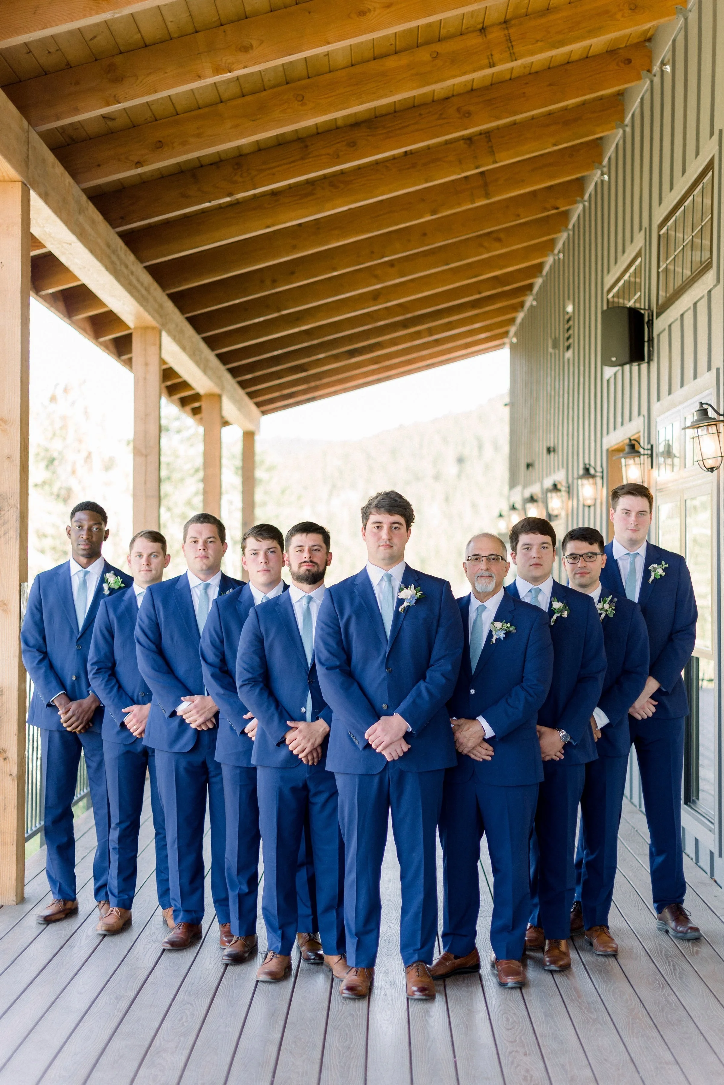 Groomsmen in sharp blue suits with light blue ties on the cocktail deck for a photo.