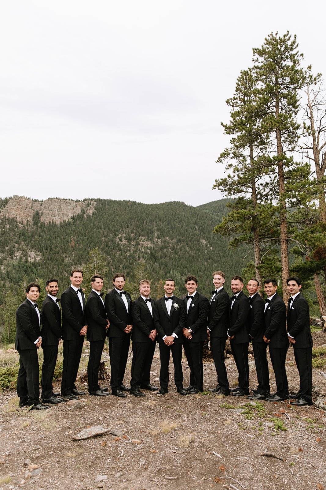groomsmen in the mountains wearing black suits and bow ties