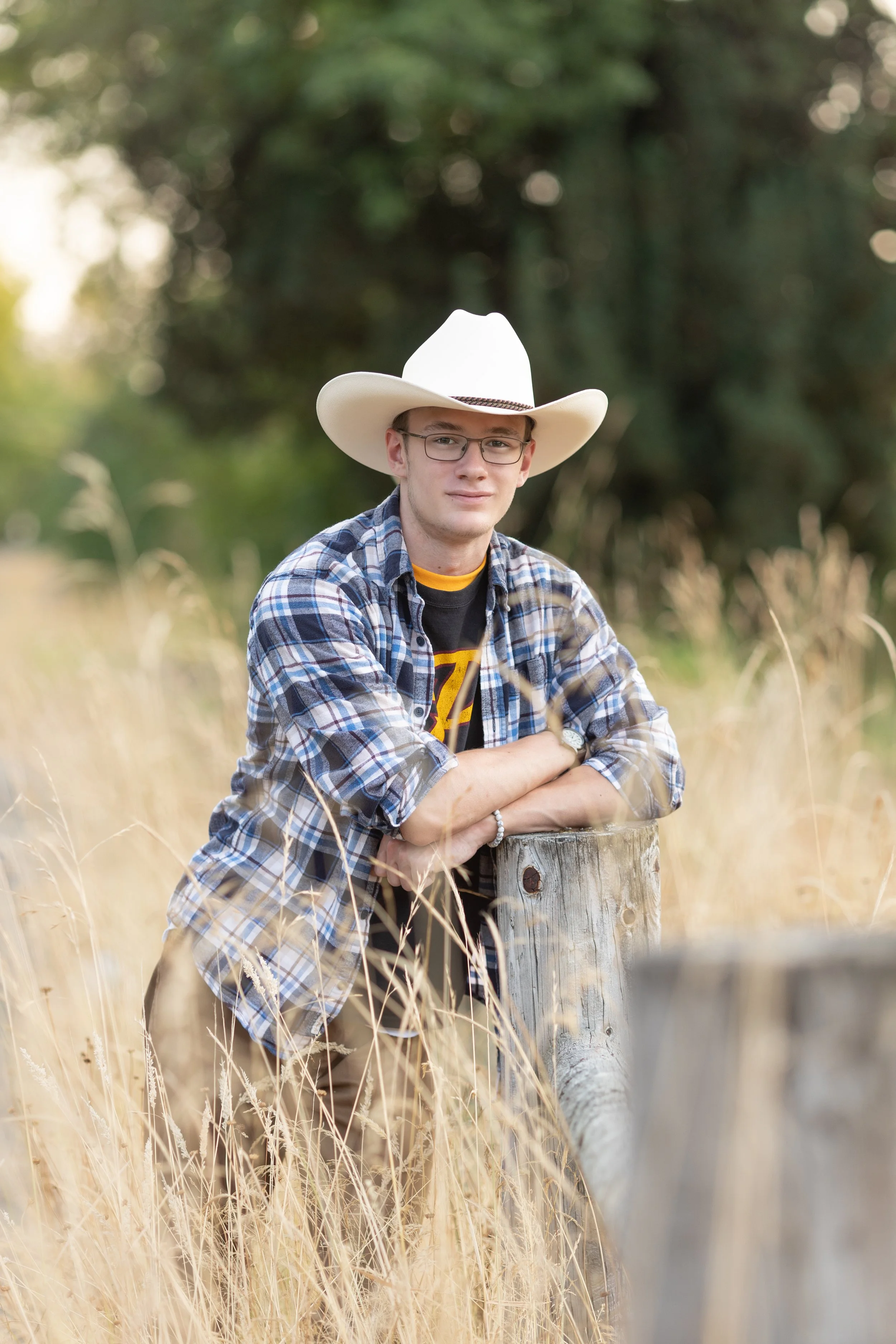 high school senior boy in tall grass wearing a hat