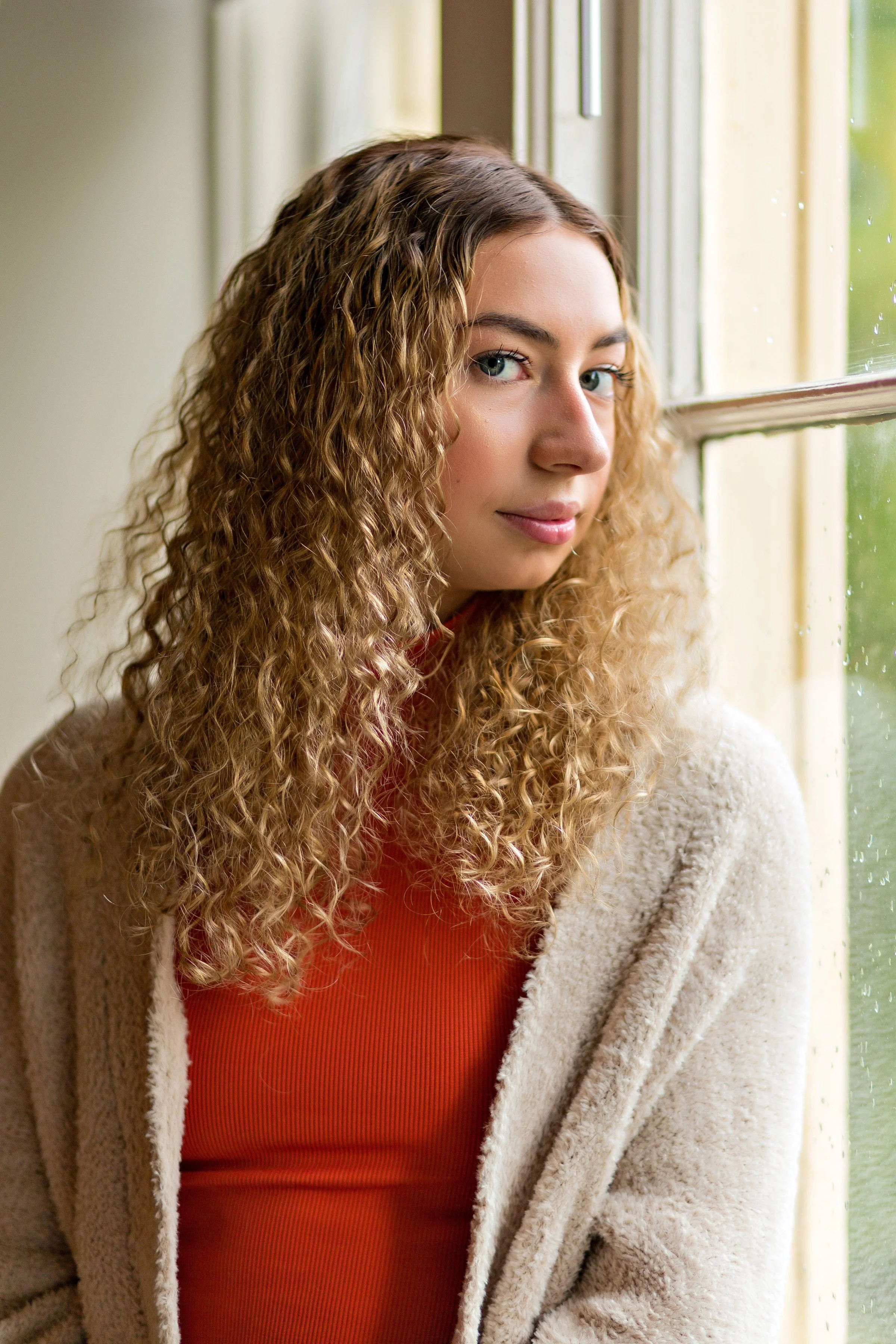 high school senior girl sitting by a window