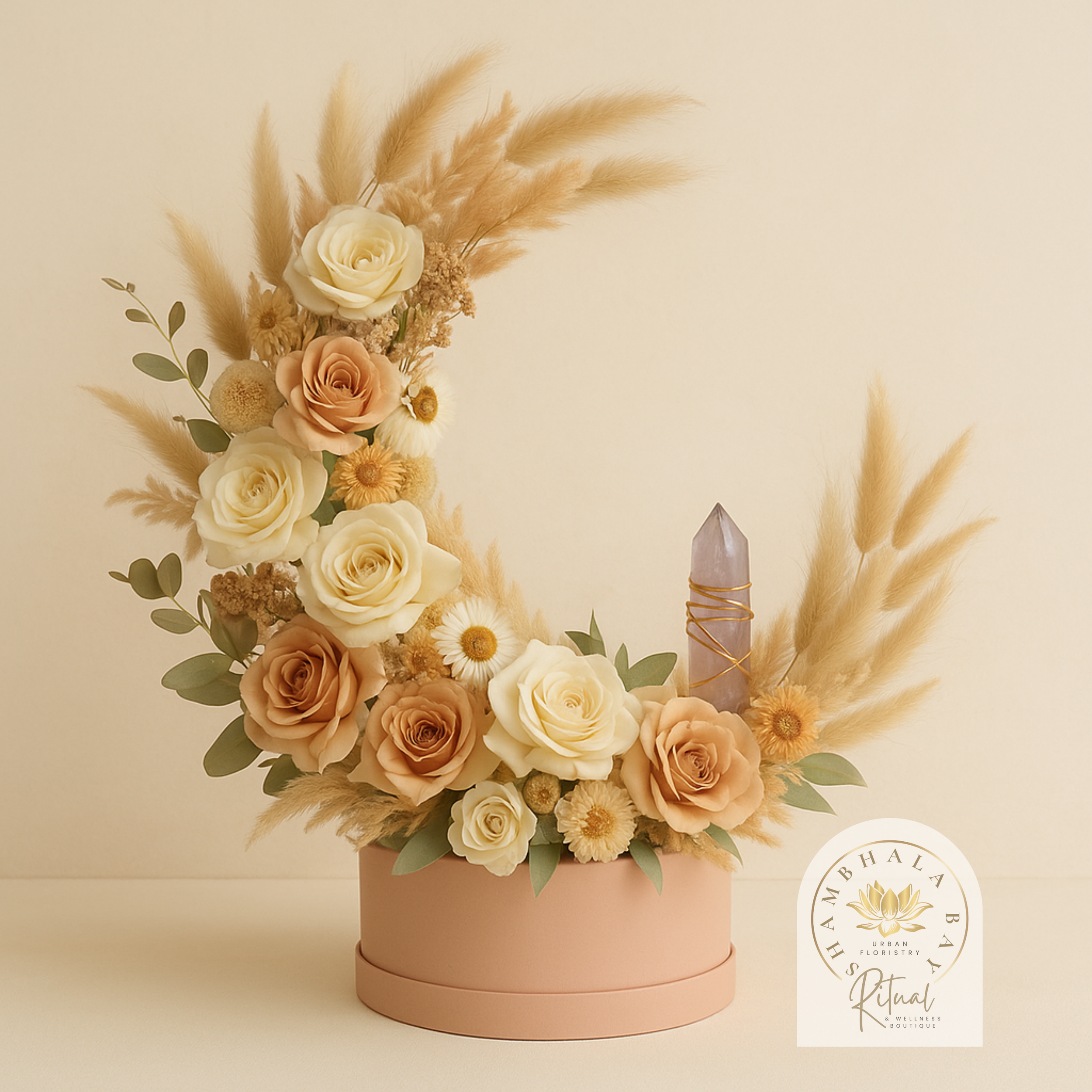 Signature Shambhala Bay Urban Floristry Bouquet. A floral arrangement with roses, daisies, and pampas grass in a light pink round box, featuring a purple crystal wrapped with gold wire.