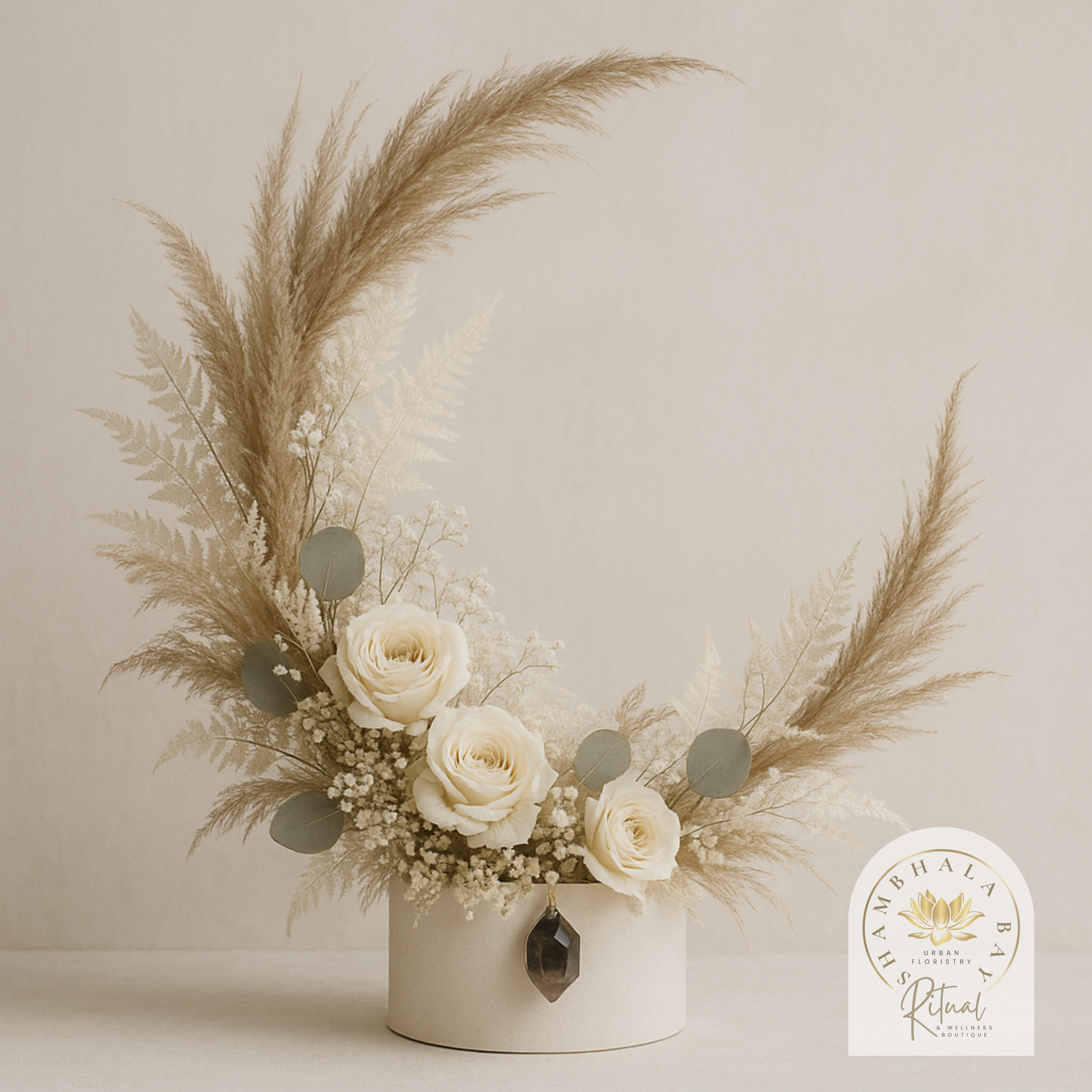 Elegant flower arrangement with white roses, baby's breath, and pampas grass in a white circular vase, featuring a black pendant, Signature Shambhala Ba design  "Shambhala Bali Urban Floristry Ritual".