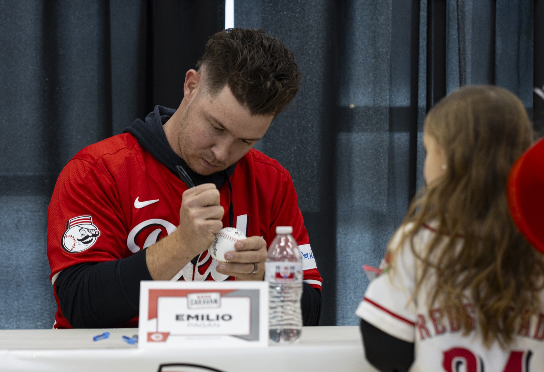 Cincinnati Reds pitcher Emilio Pagán autographs a baseball for a young fan at the Reds Caravan event at the Athens Community Center in Athens, Ohio, Jan. 24, 2025. | For The Post