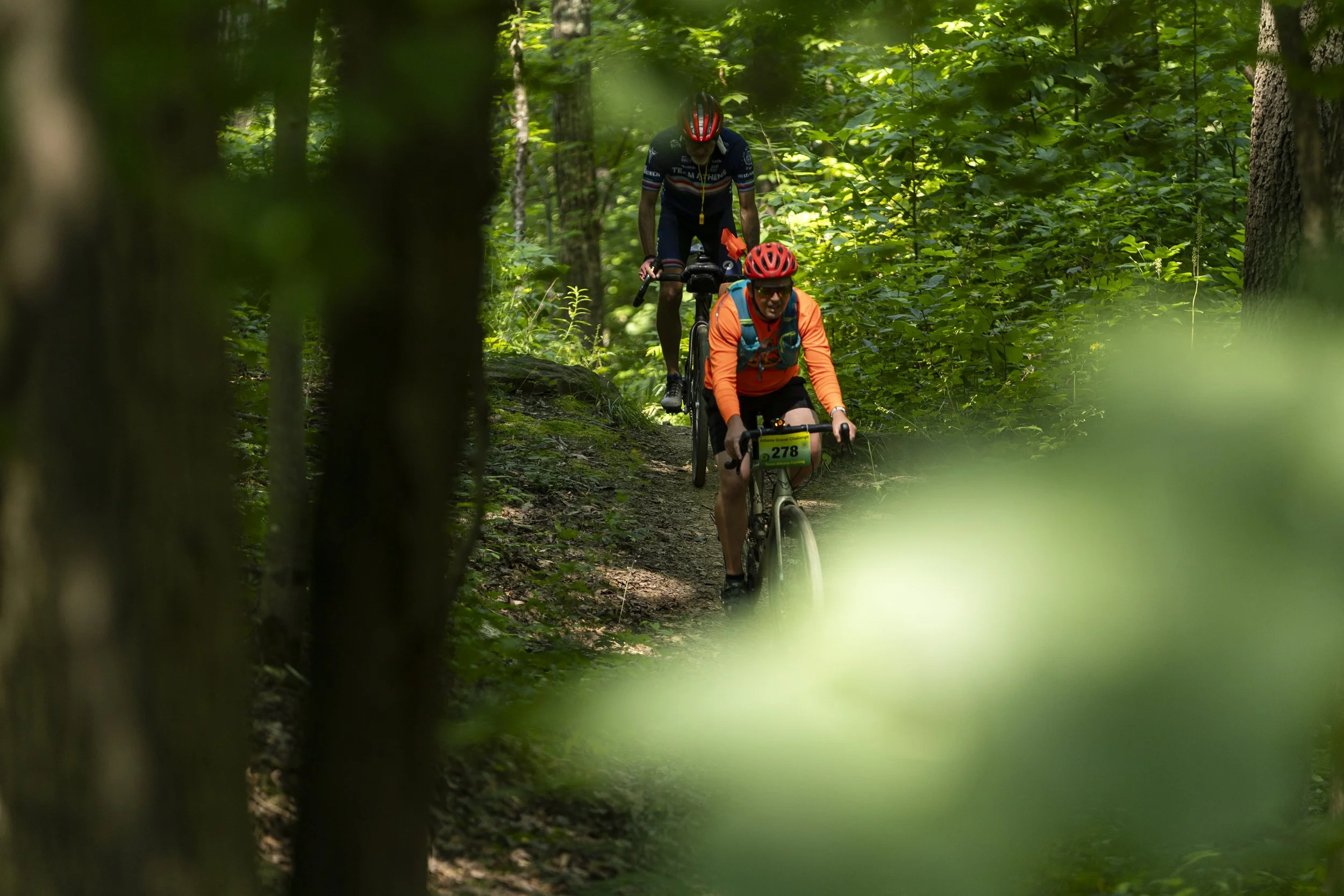 Cyclists ride down the Holler Collar Trail during the Athens Gravel Challenge on the Bailey's Trail System in Wayne National Forest, Ohio, July 26, 2026. 2026 marked the first year of the race since 2024, as it was cancelled due to inclement weather 