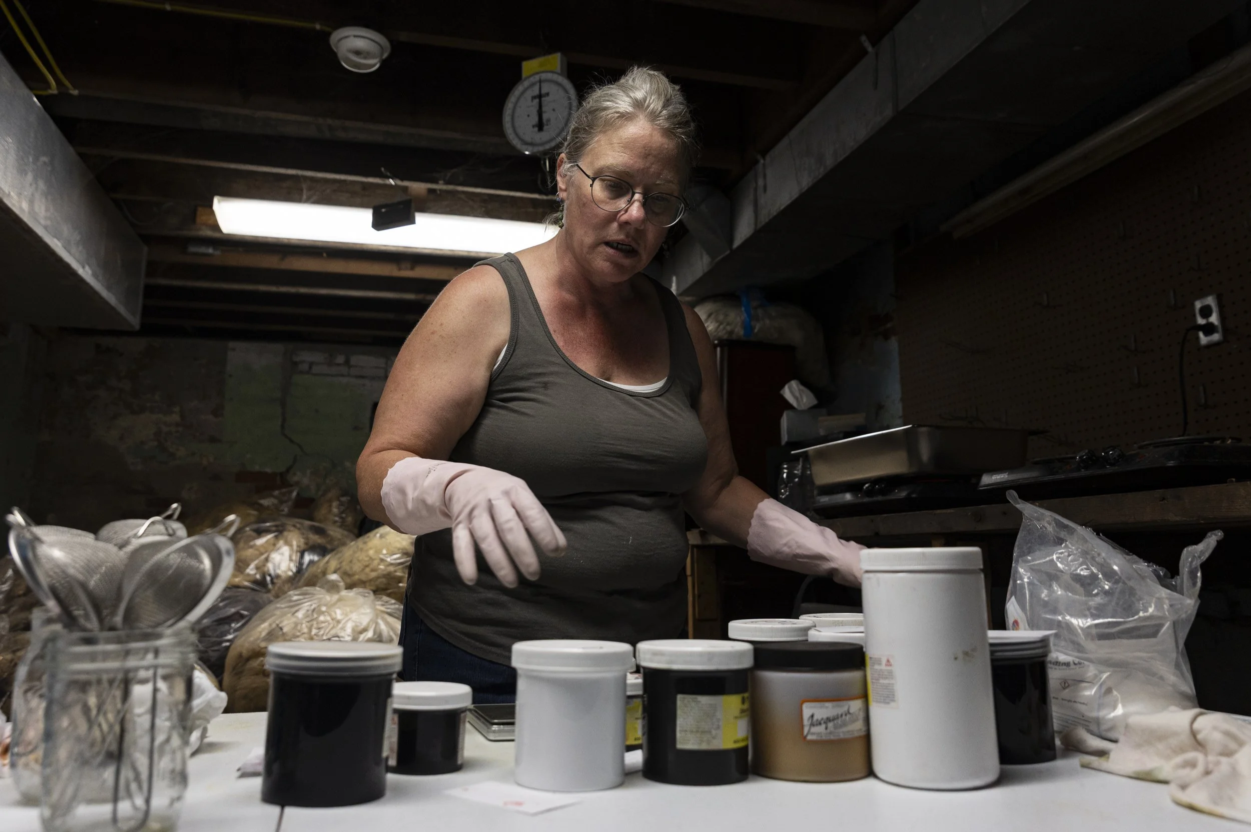 Lisa Heinz grabs for jar of dye in her basement in Athens, Ohio, September 2, 2025.