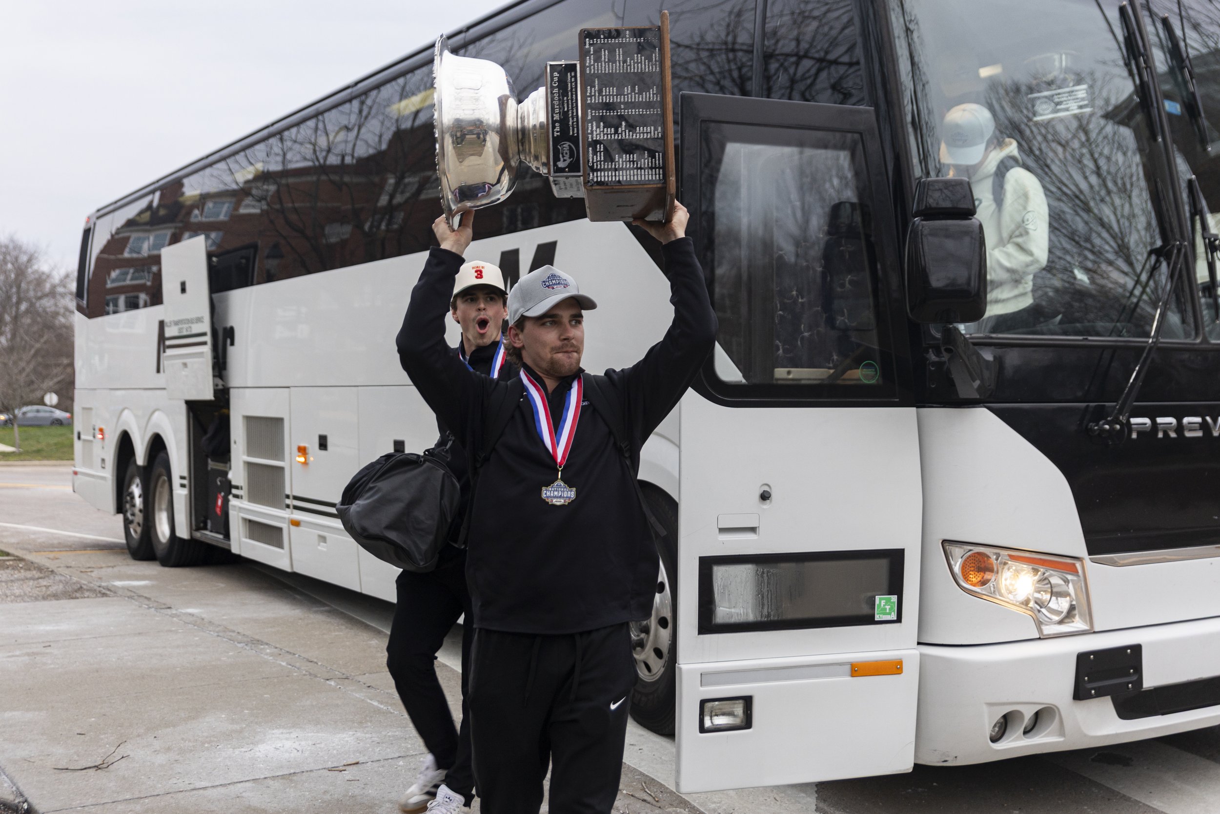 Ohio Bobcats forward and captain Jack Glen raises the ACHA tournament trophy as he gets off the bus from St. Louis outside Bird Arena in Athens, March 18, 2026. The Bobcats  beat Adrian College to take their first National Championship win since 2004