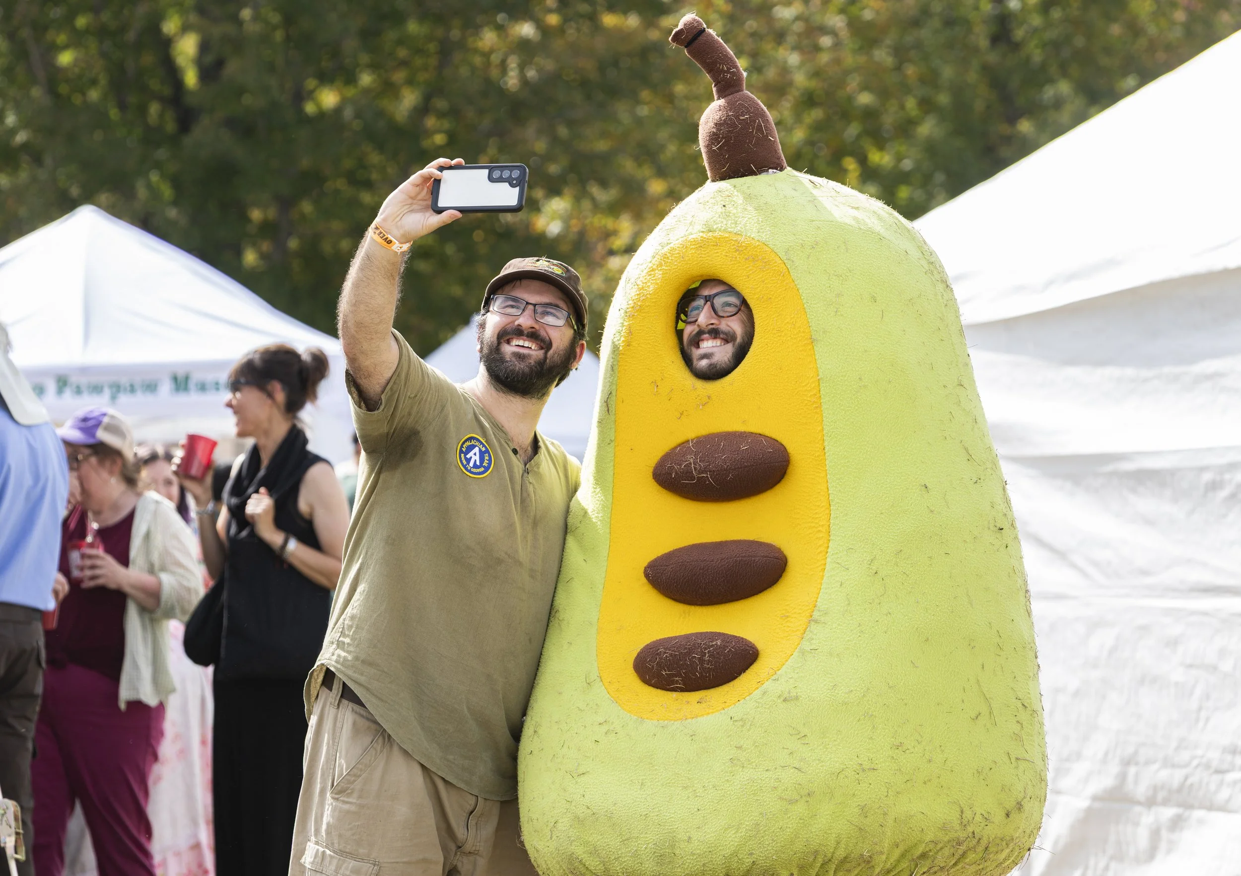 Attendees take pictures in a pawpaw costume at the Pawpaw Festival at Lake Snowden in Albany, Ohio, Sep. 13, 2025. | For The Post