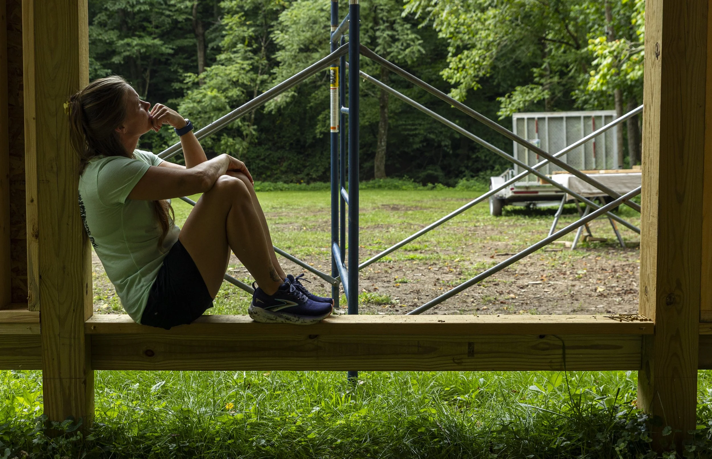 Natalie Bott looks up while sitting on a wooden beam of a treehouse that is currently in the course of being built on her and her husband Casey's property at The Treehouses at Owl Hollow in Monroe County, Ohio, Aug. 9, 2026. The couple hopes to bring