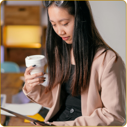 An Asian American woman drinks a coffee while doing analyses