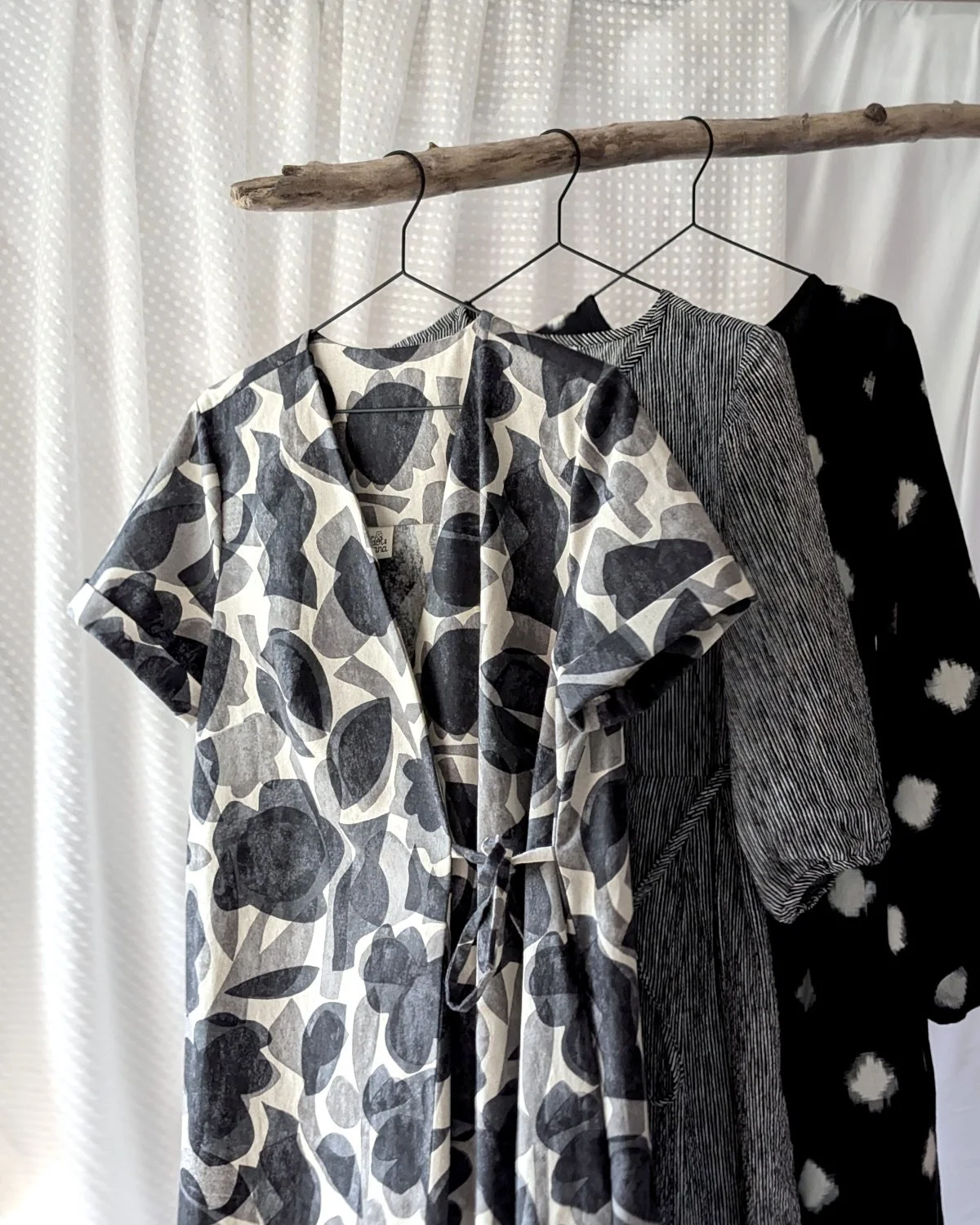 3 black and white dresses hanging from some driftwood