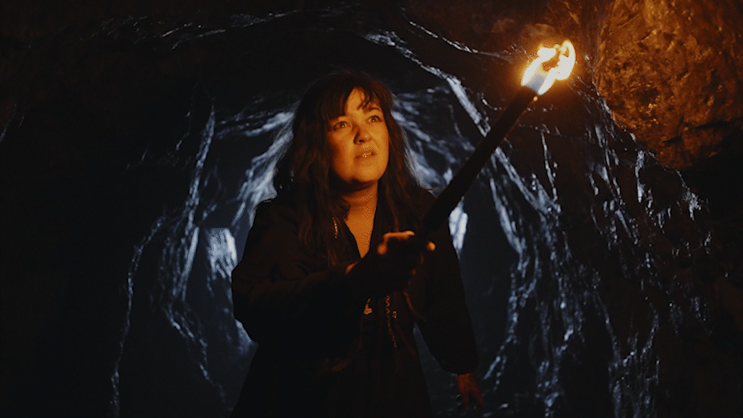 Woman holding a lit torch inside a dark cave