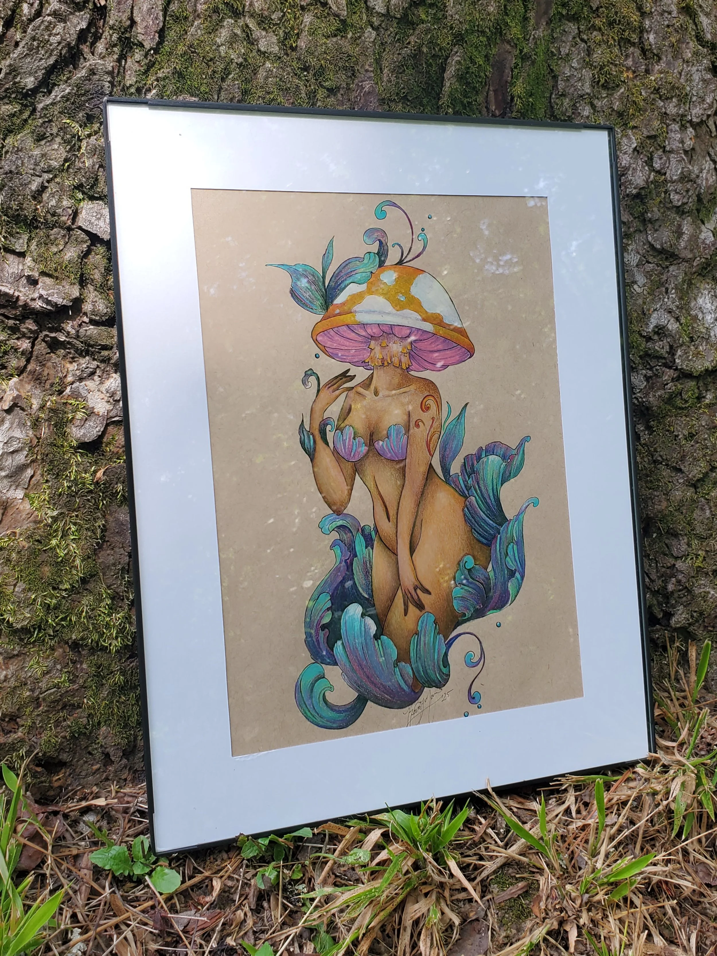 A framed artwork of a woman with a mushroom cap as her head, surrounded by abstract plant elements, displayed in simple frame and white matting