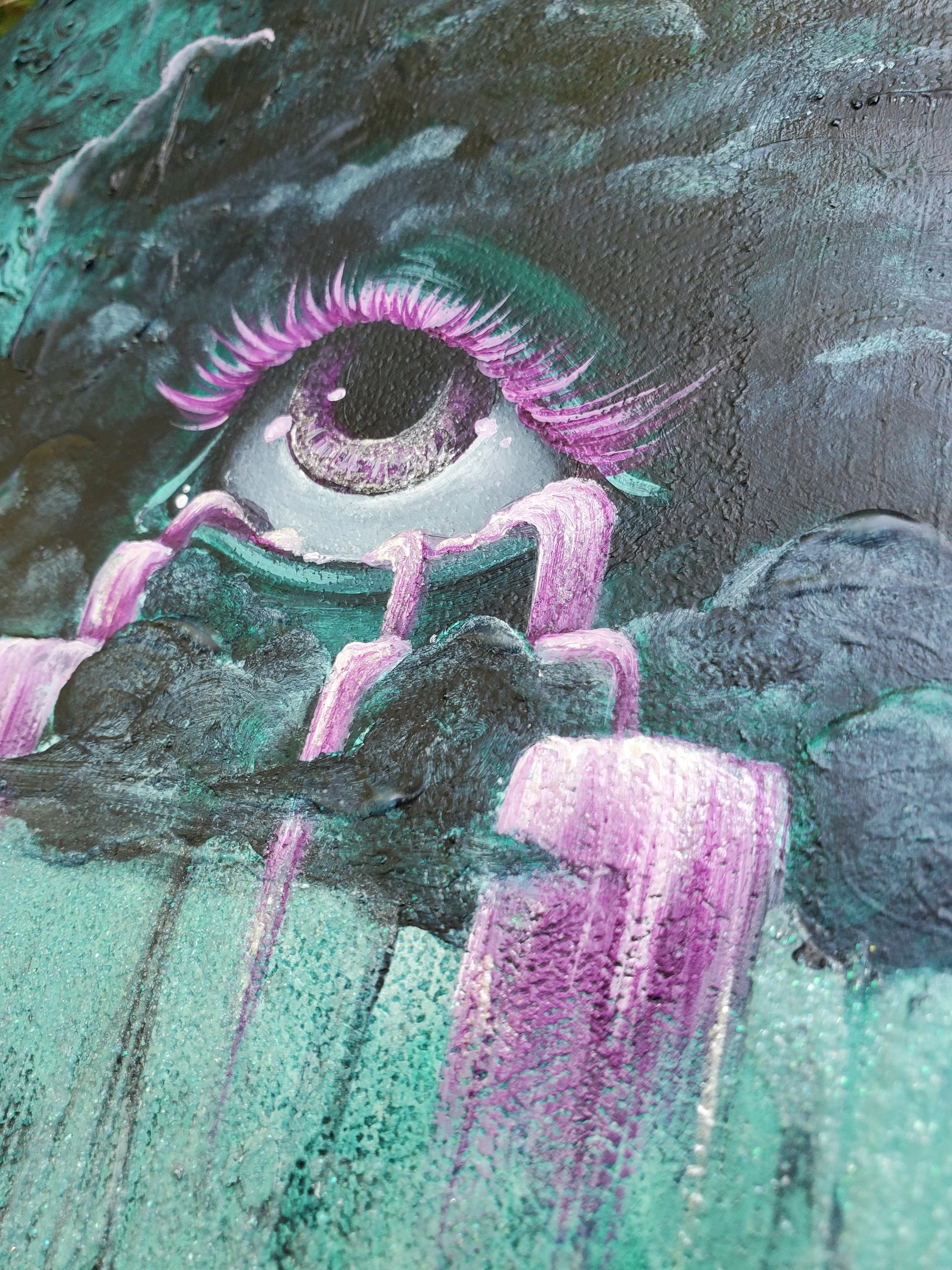Close-up of a colorful painted eye on a textured surface, featuring purple, pink, green, and black hues.