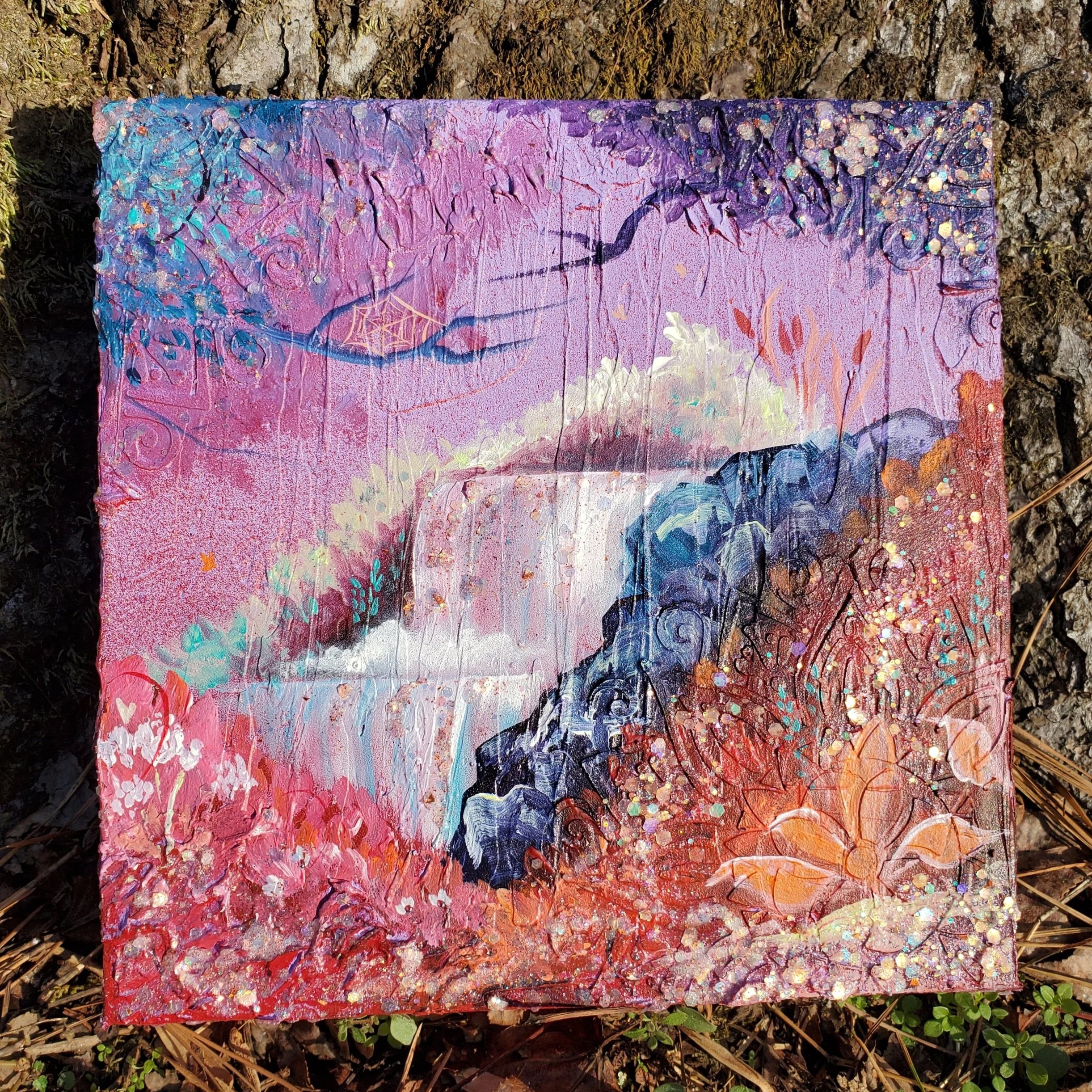 An acrylic painting with pink, purple, blue, and red hues, decorated with glitter and abstract woodland designs.