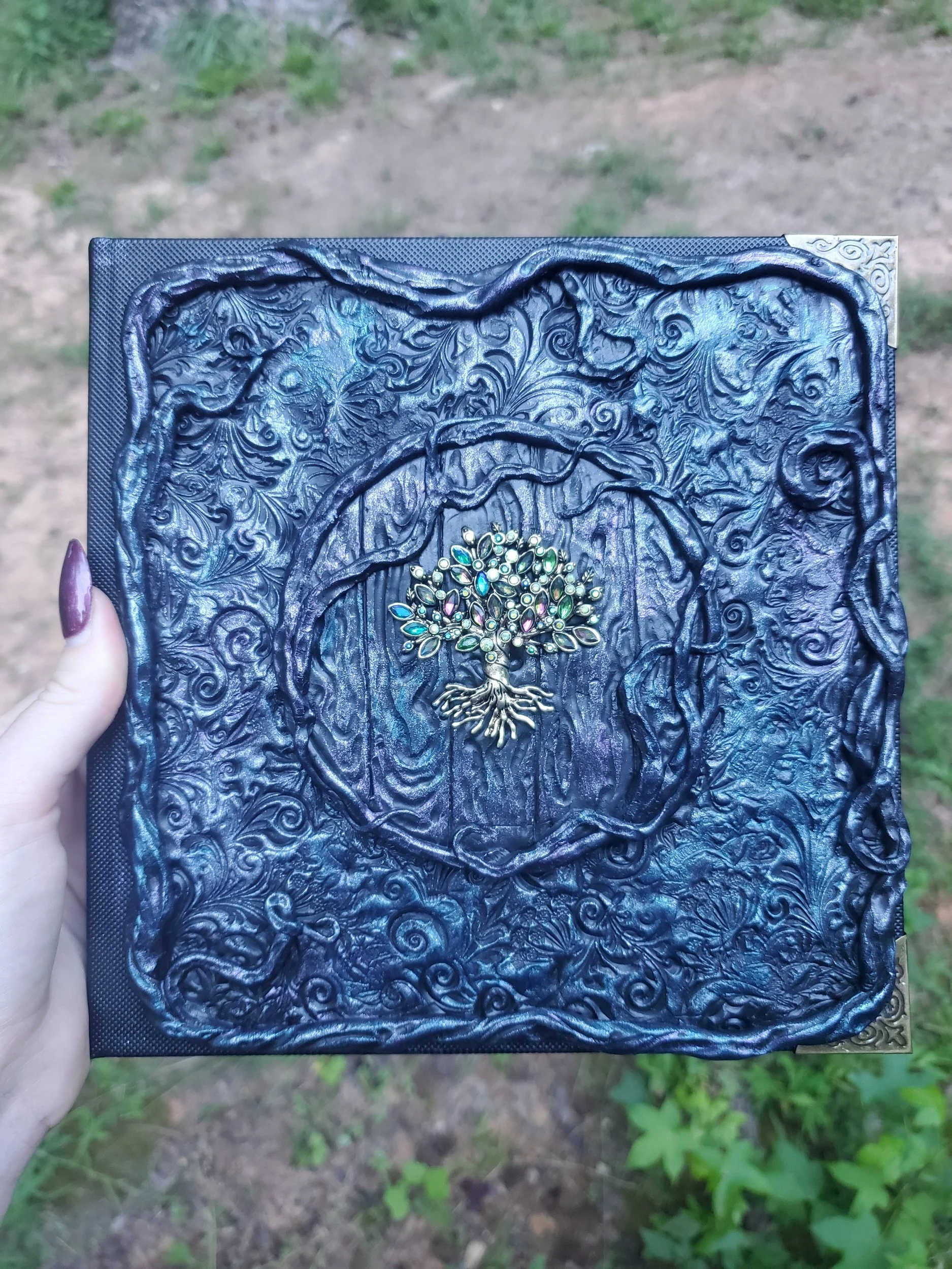 Decorative black notebook with intricate swirls and a colorful gemstone tree centerpiece