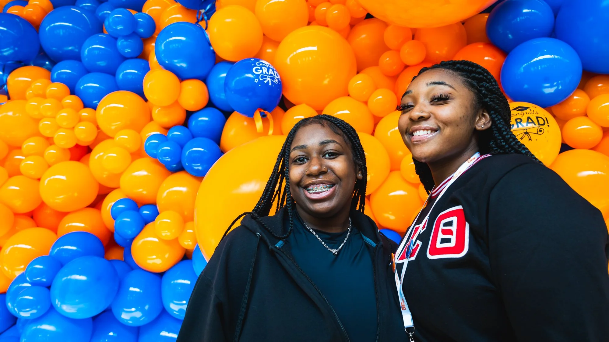 Photo of two black female Hope Scholars smiling in front of orange and blue balloons.