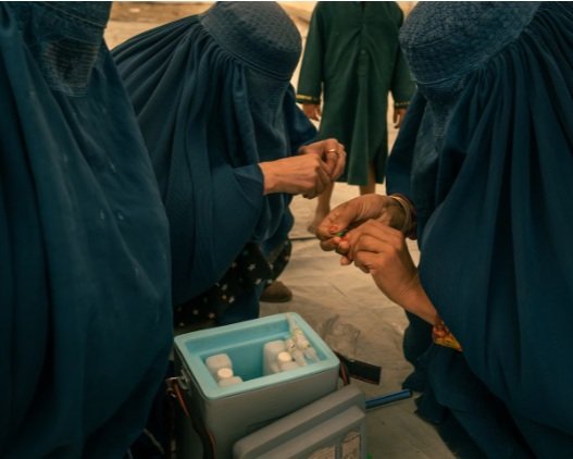 Vaccinators prepare polio vaccines they are tasked to administer to returnees deported from Pakistan  (Elise Blanchard for The Washington Post)