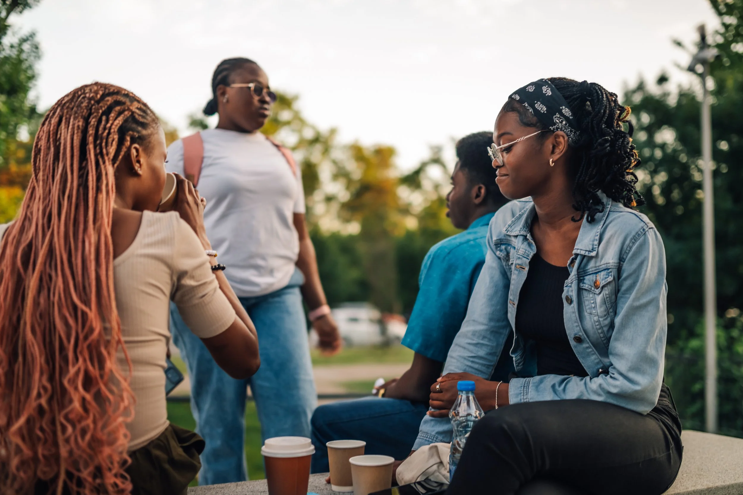 A group of young Black adult women acting as college students, with one drinking coffee and another walking, highlighting the Breaking the Cycle Therapy Group at Neutral Ground Counseling Group in Fairfax, VA.