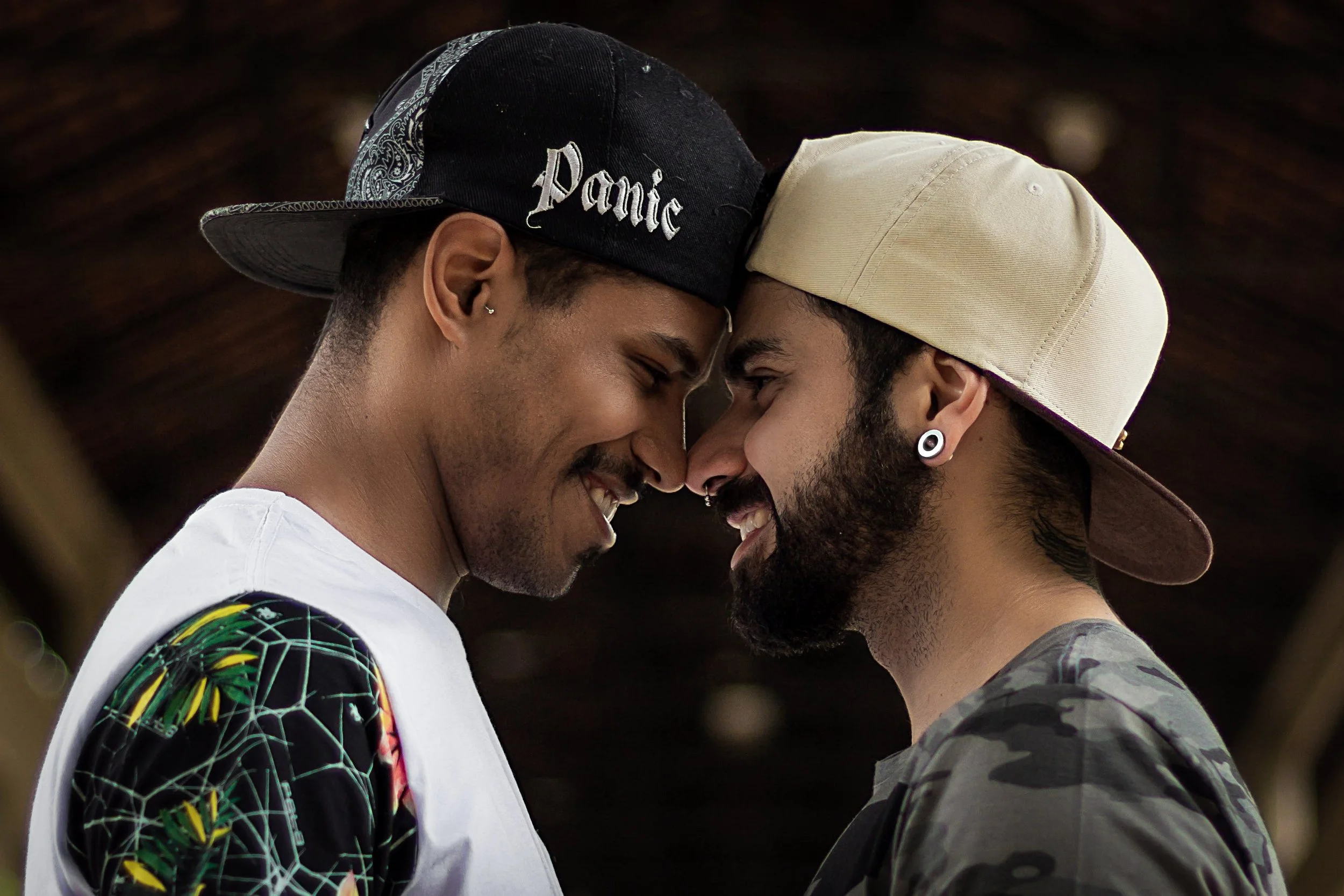 A gay BIPOC couple smiling warmly with their faces close together, representing inclusive, identity-affirming relationship counseling at Neutral Ground Counseling Group in Fairfax, VA.