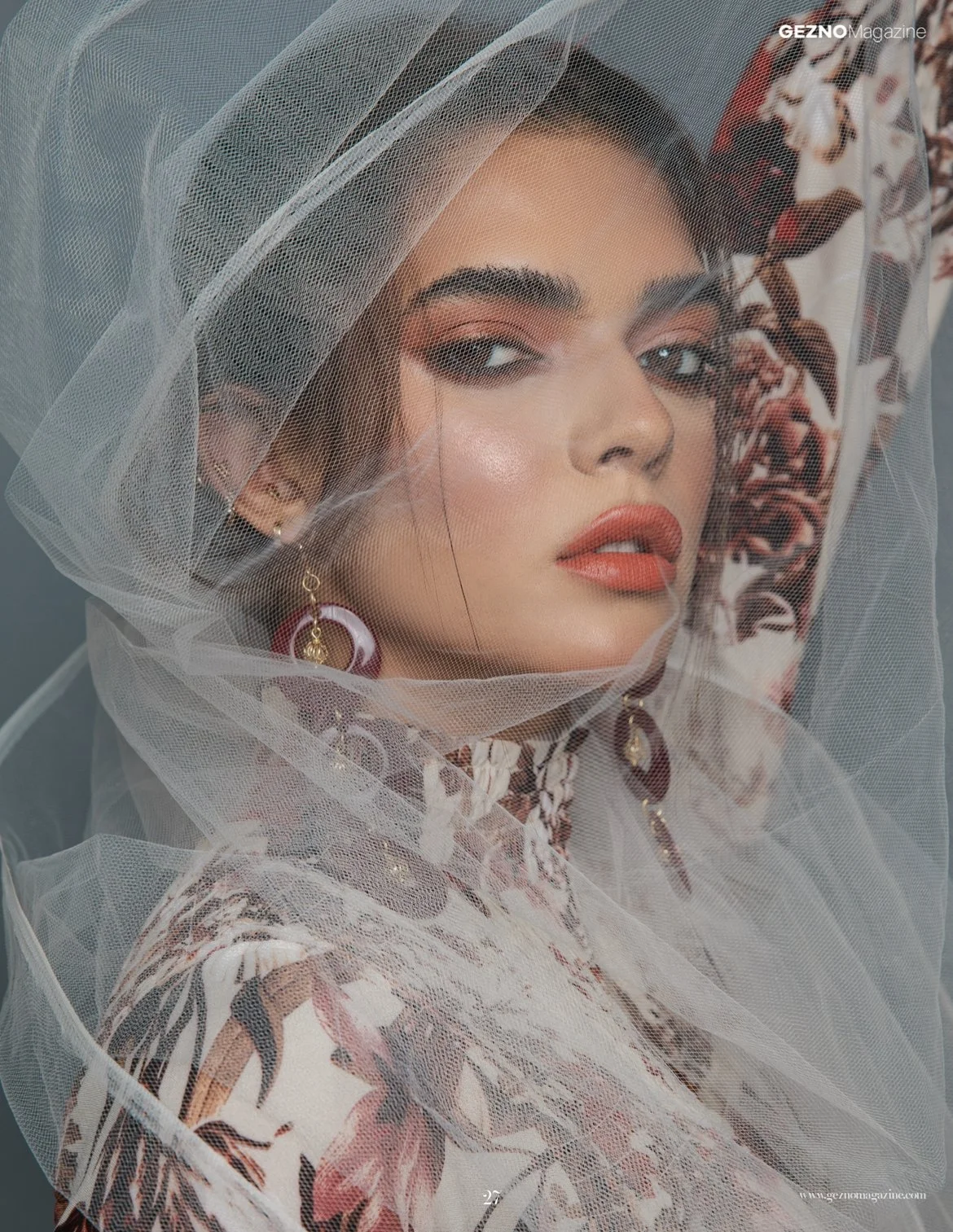 Woman wearing floral dress and veil with bold makeup and red lipstick.