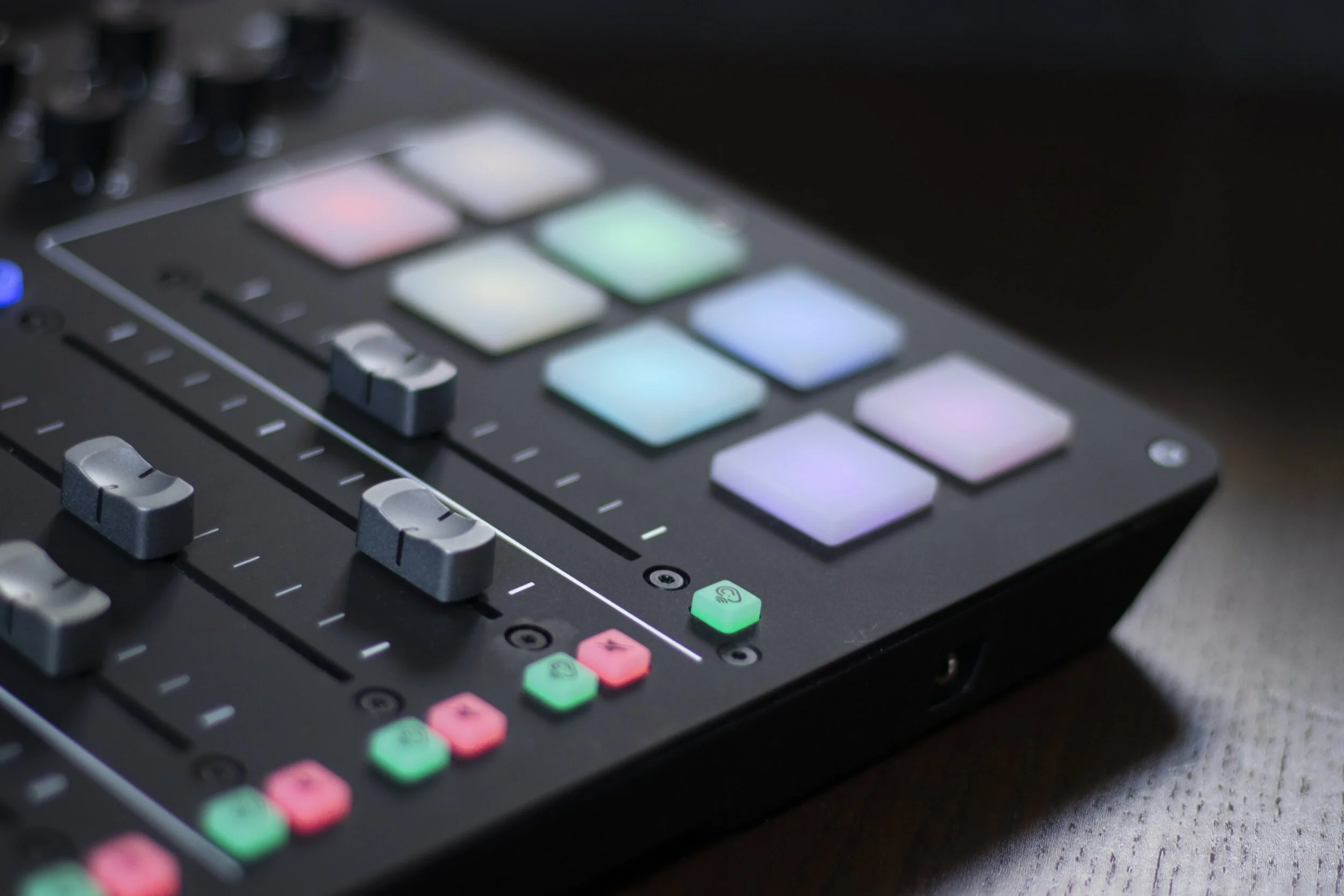 A music production controller with colorful pads and knobs on a dark surface.