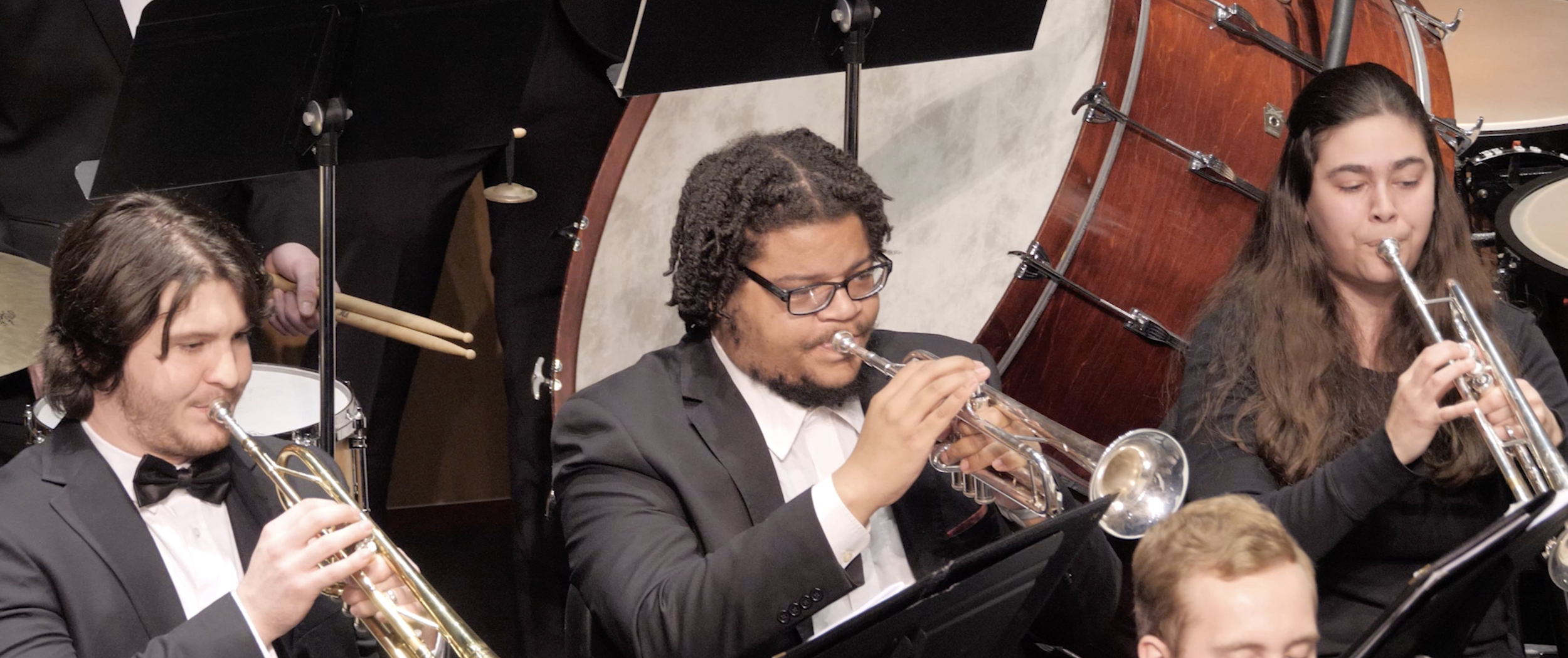 Orchestra musicians with brass and percussion instruments performing on stage