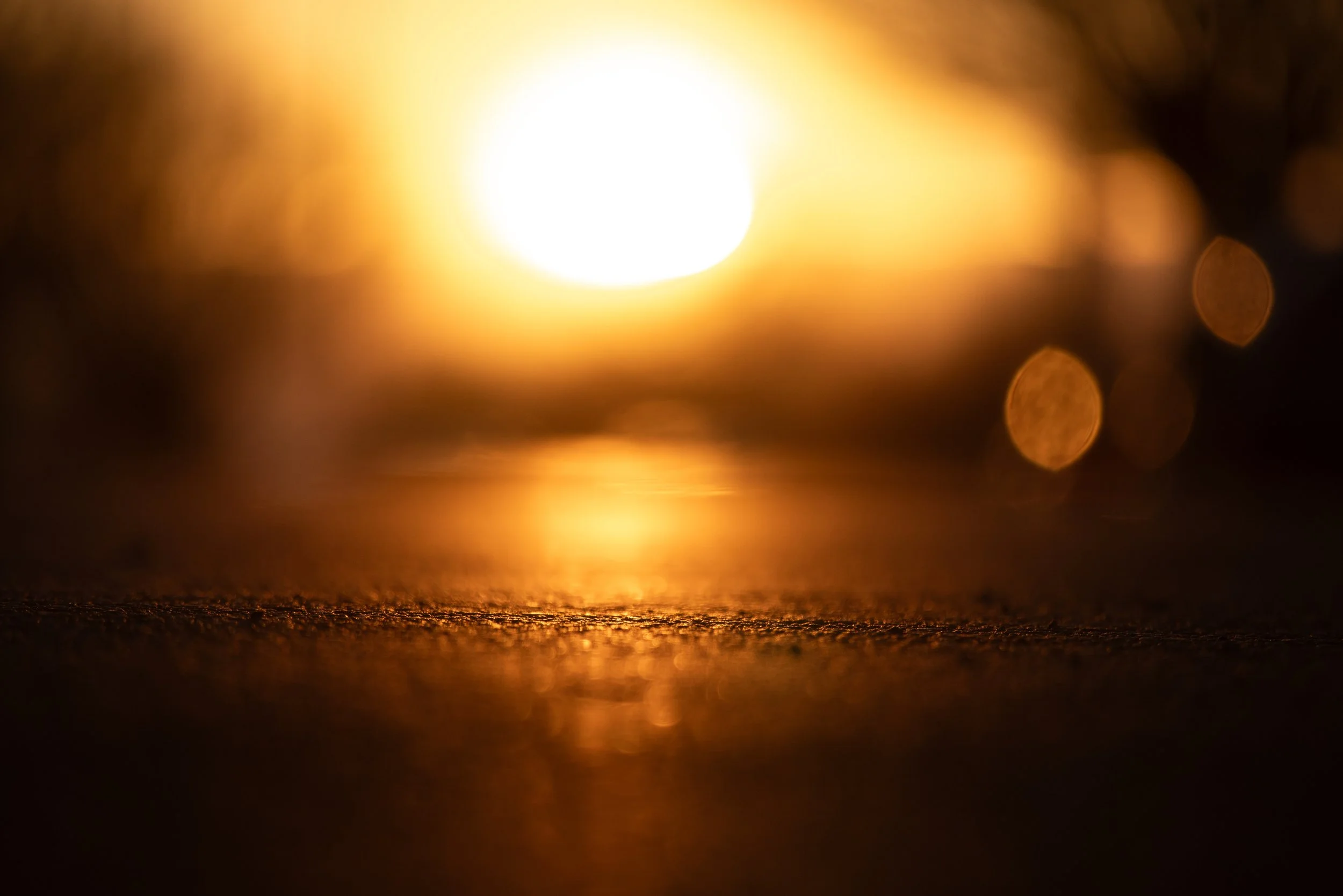 Blurred image of a bright, glowing sunset over water with bokeh effects.