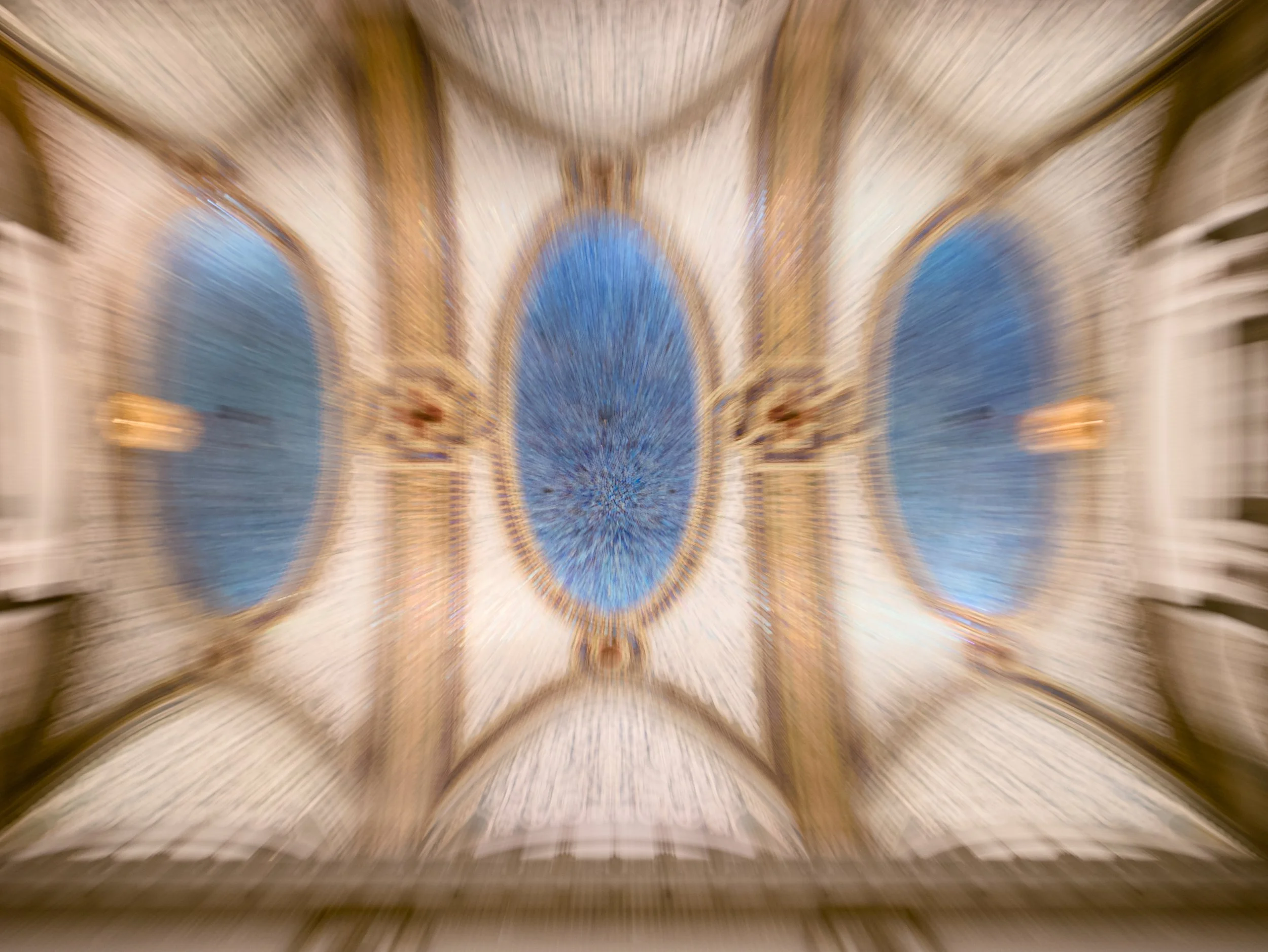 A blurred photograph of an ornate cathedral ceiling with intricate designs and blue accents.