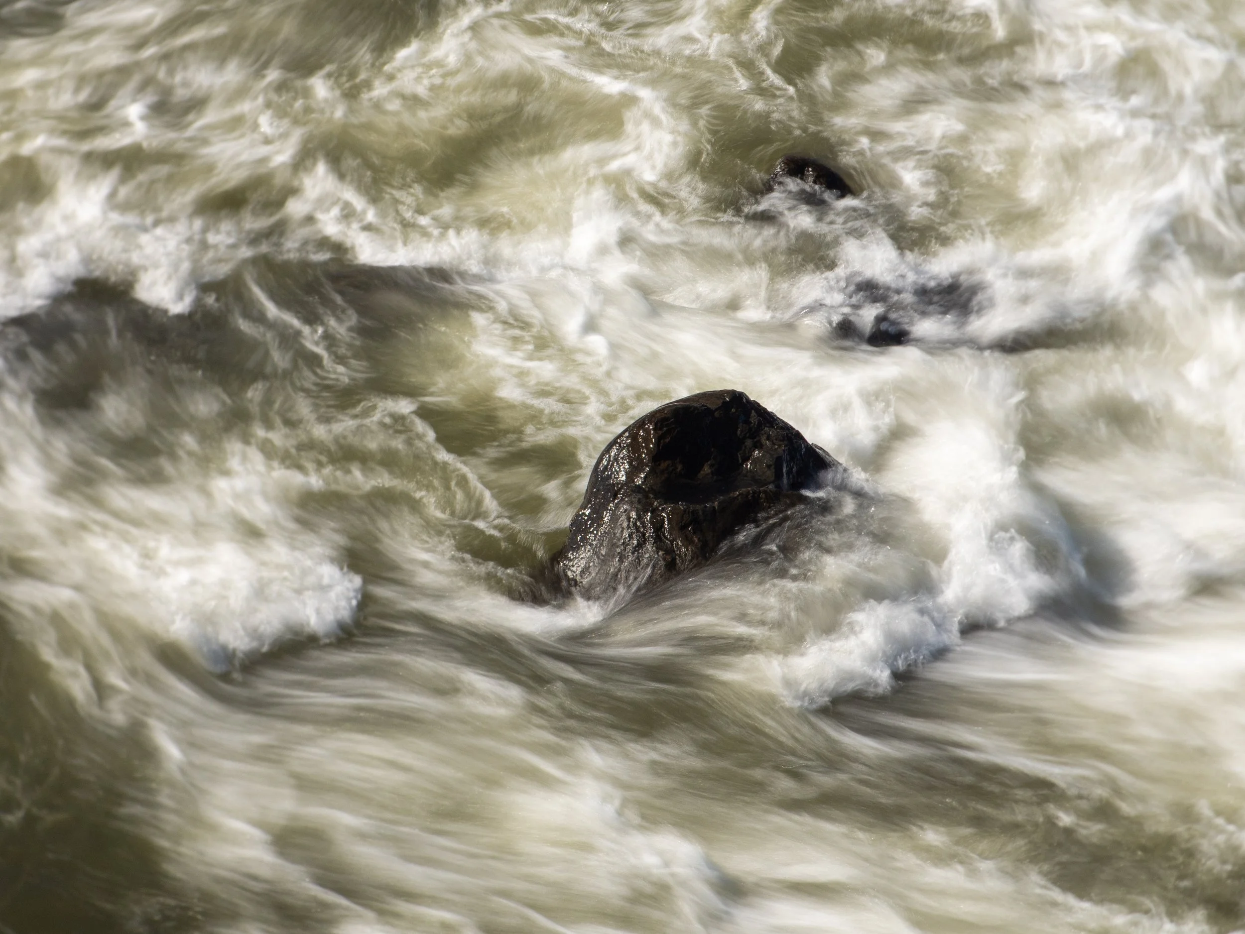 Waves crashing against rocks in turbulent water.