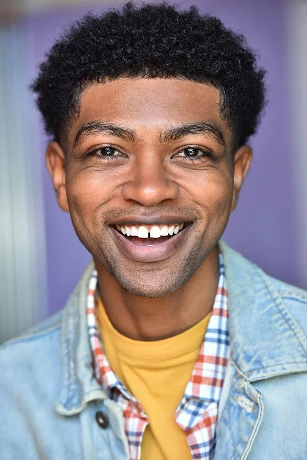 Professional male commercial headshot with a genuine smile and lavender background, captured by Marc Cartwright, Los Angeles actor headshot photographer.